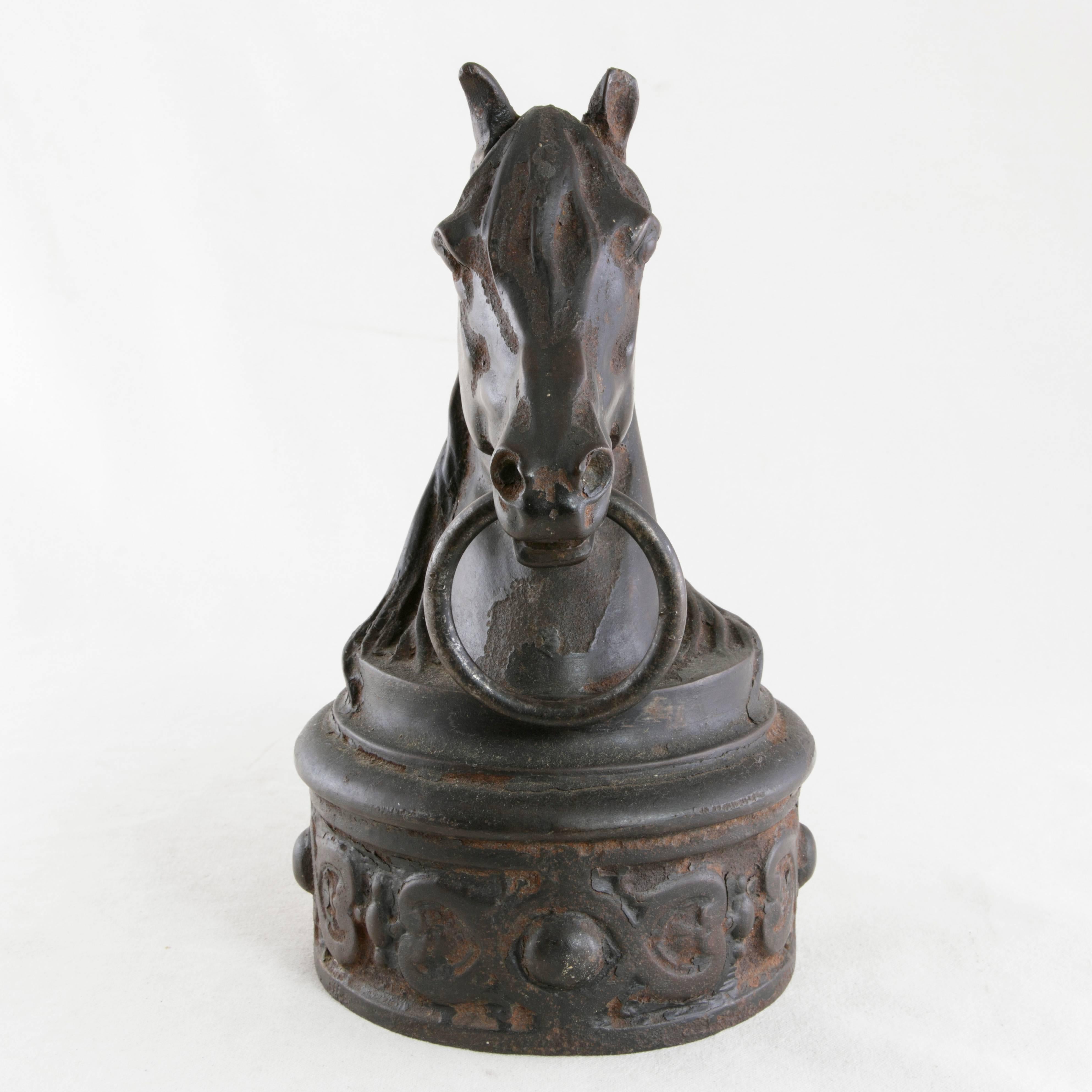 Originally placed on top of a post in 19th century, France, this cast iron horse hitch features a horse's head holding a ring in its mouth. Bridle reins would have been tied to the ring once the rider dismounted. The horse's head rests on a