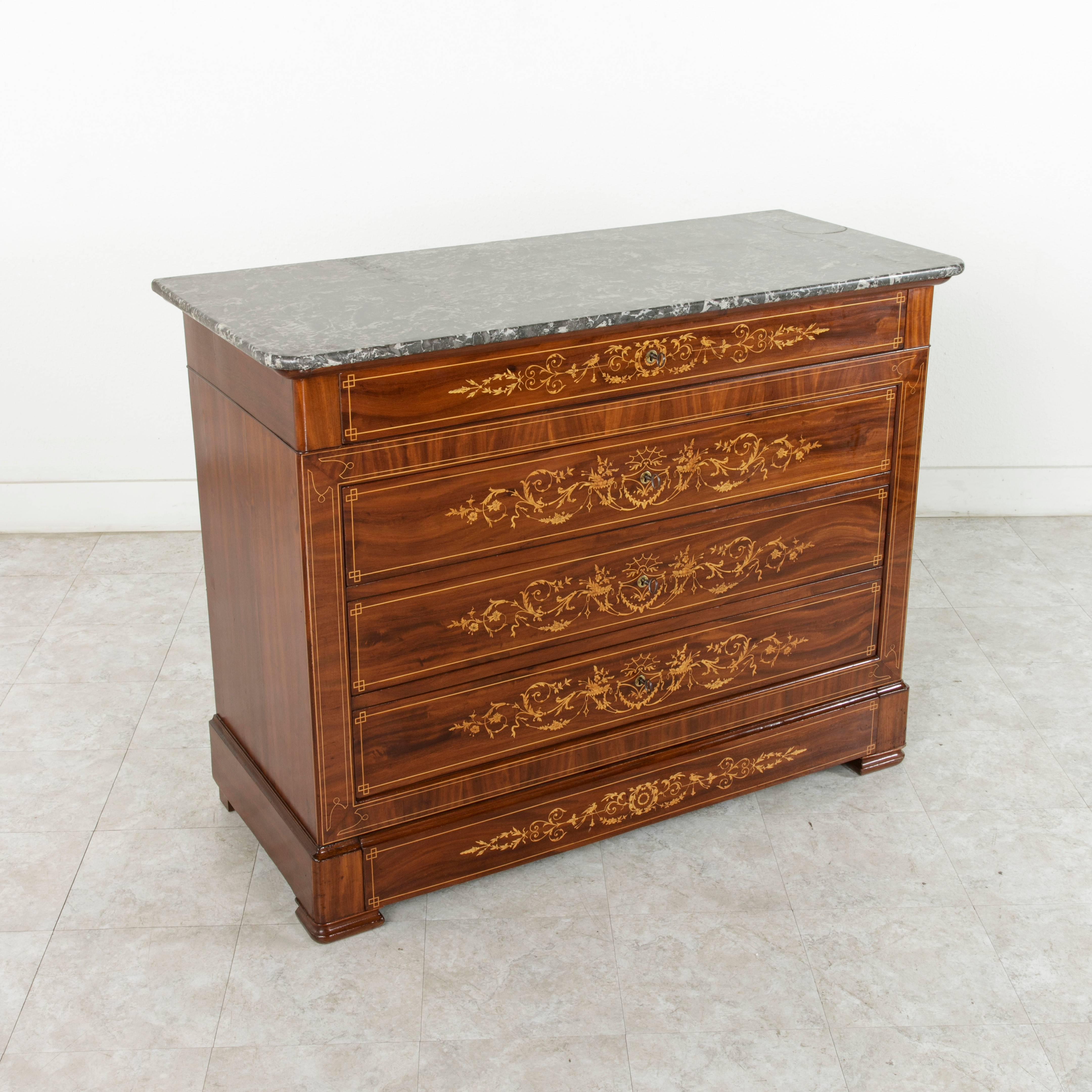 A rare piece from a short period of time in French furniture making, this Charles X period mahogany marquetry chest features finely inlaid lemon wood outlining the facade and each drawer front of the piece. Intricately scrolled leaves in lemon wood