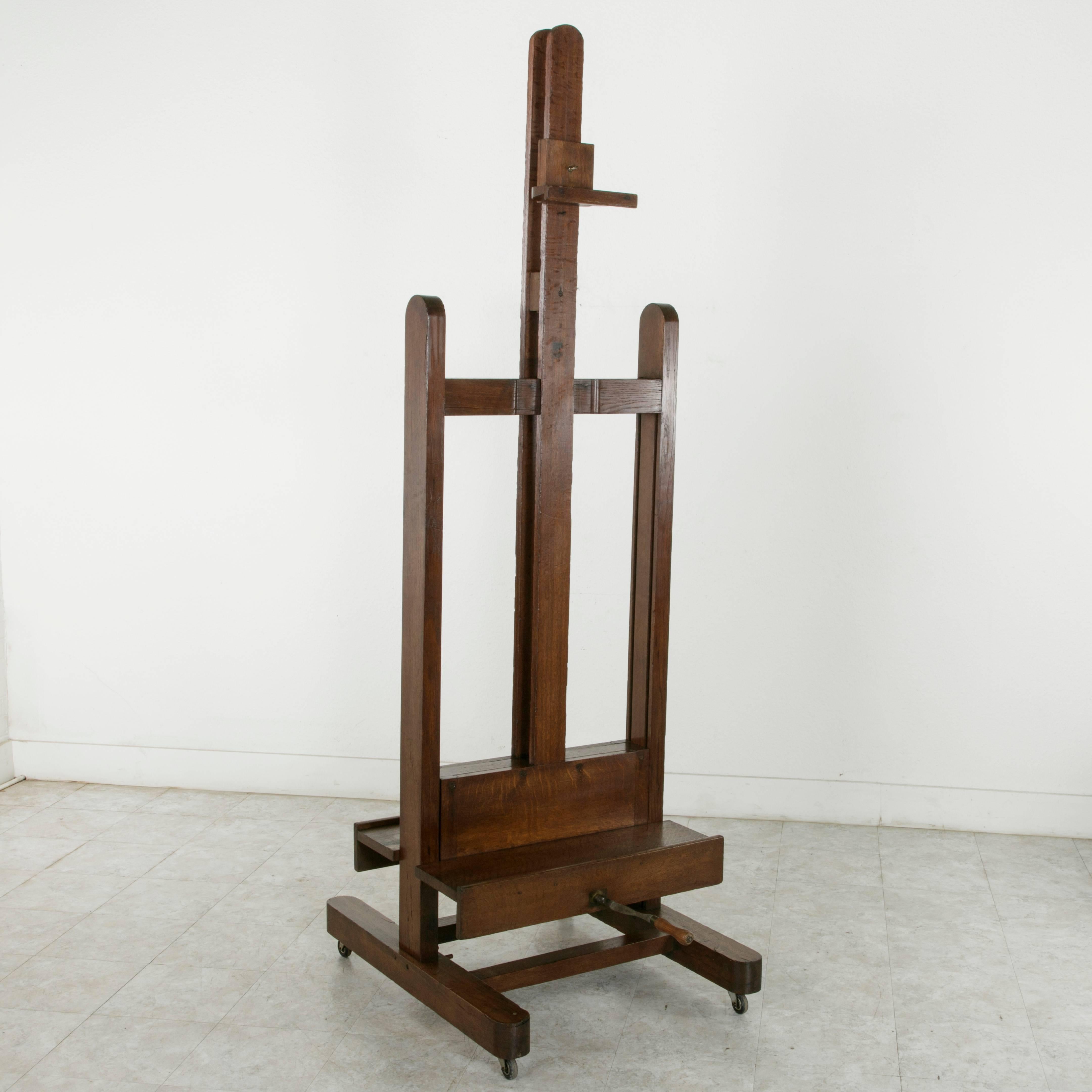 This very large French oak floor easel from the early twentieth century is a rare find.  It is double faced, allowing for display of a painting on each side.  Its iron and wooden crank allows for an adjustable height ranging from 84 to an amazing