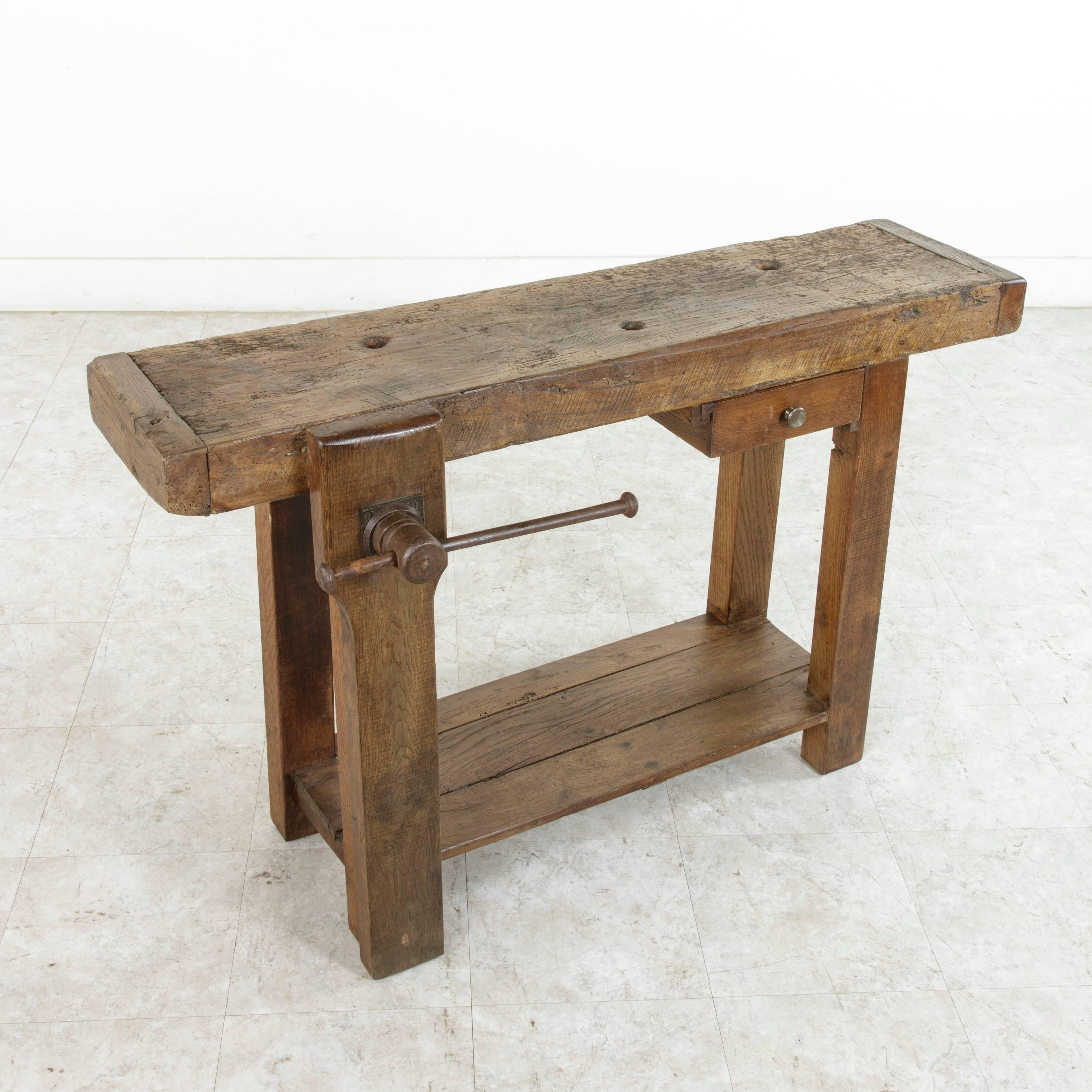 This early 20th century workbench from Normandy, France, is constructed of solid oak and features a three and one half inch thick top with a single lower drawer. The vice grip on the side can be positioned so that a hand towel can be hung from it,