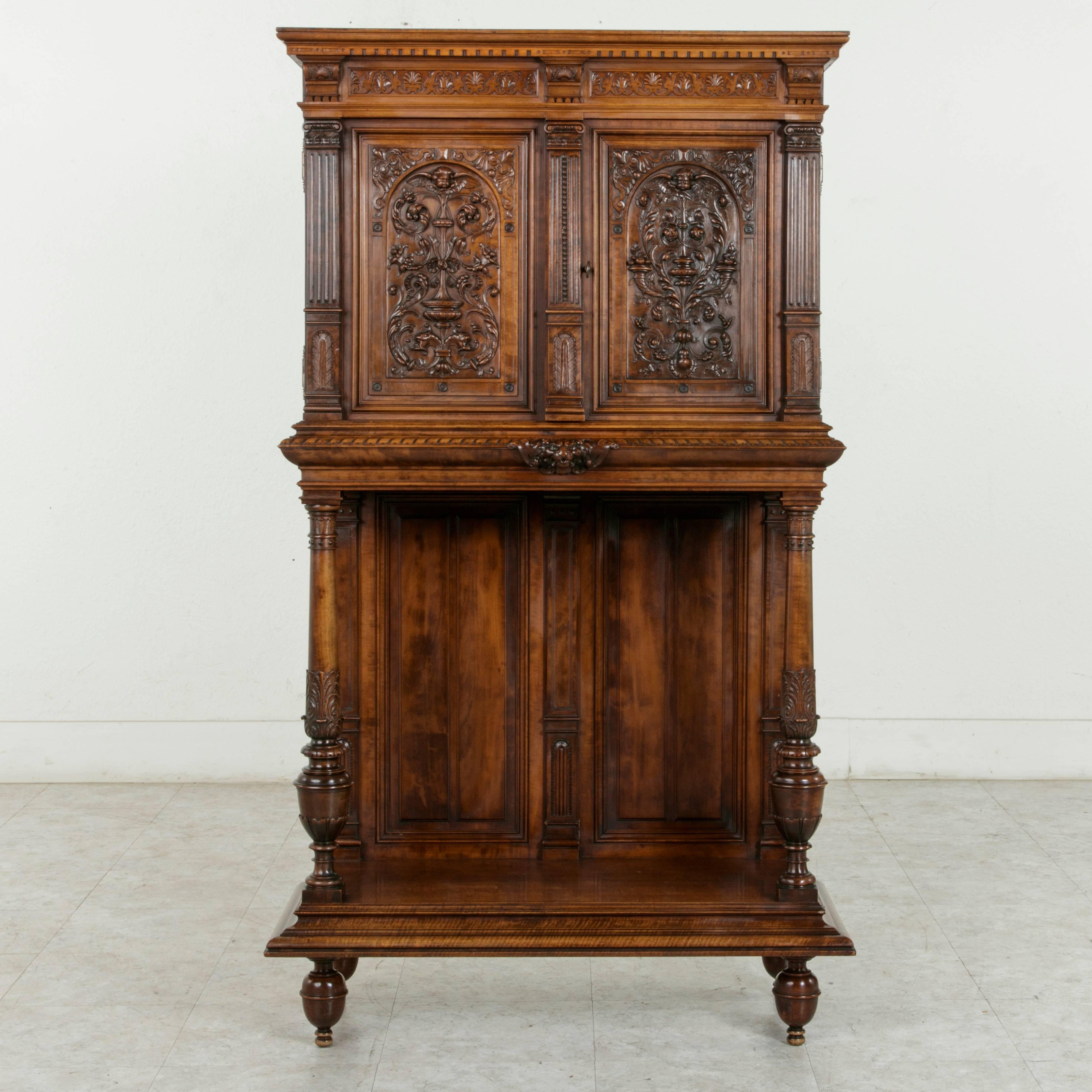 A finely hand-carved piece from the late 19th century, this French walnut Renaissance style cabinet features an upper compartment detailed with three fluted square ionic columns. The two doors of the upper cabinet are lavishly hand-carved with