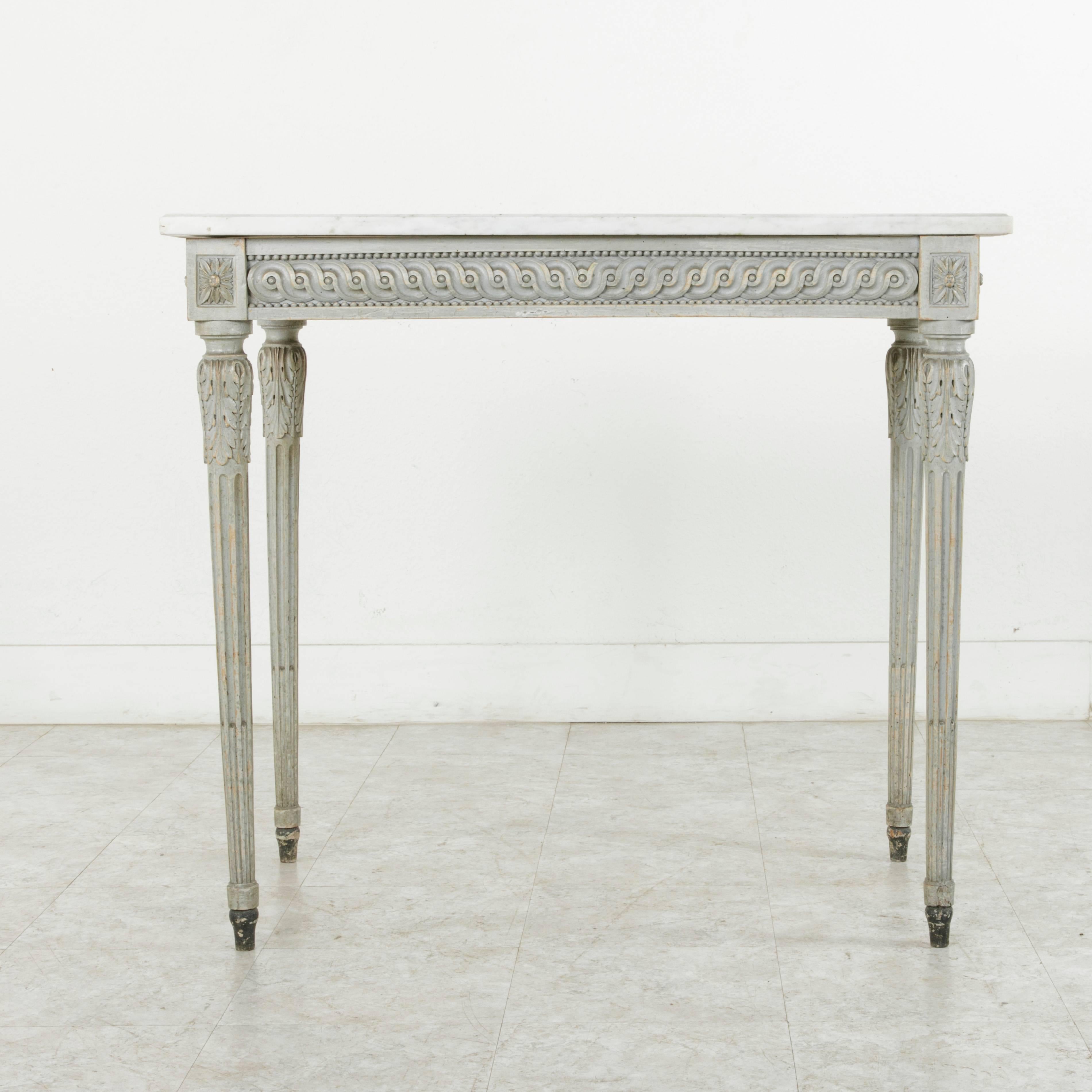This French Louis XVI style console table from the nineteenth century features finely hand carved detailing of classic Louis XVI motifs on three sides.  Interlaced scrolling between rows of beading are joined by rosettes at the die joints. Resting