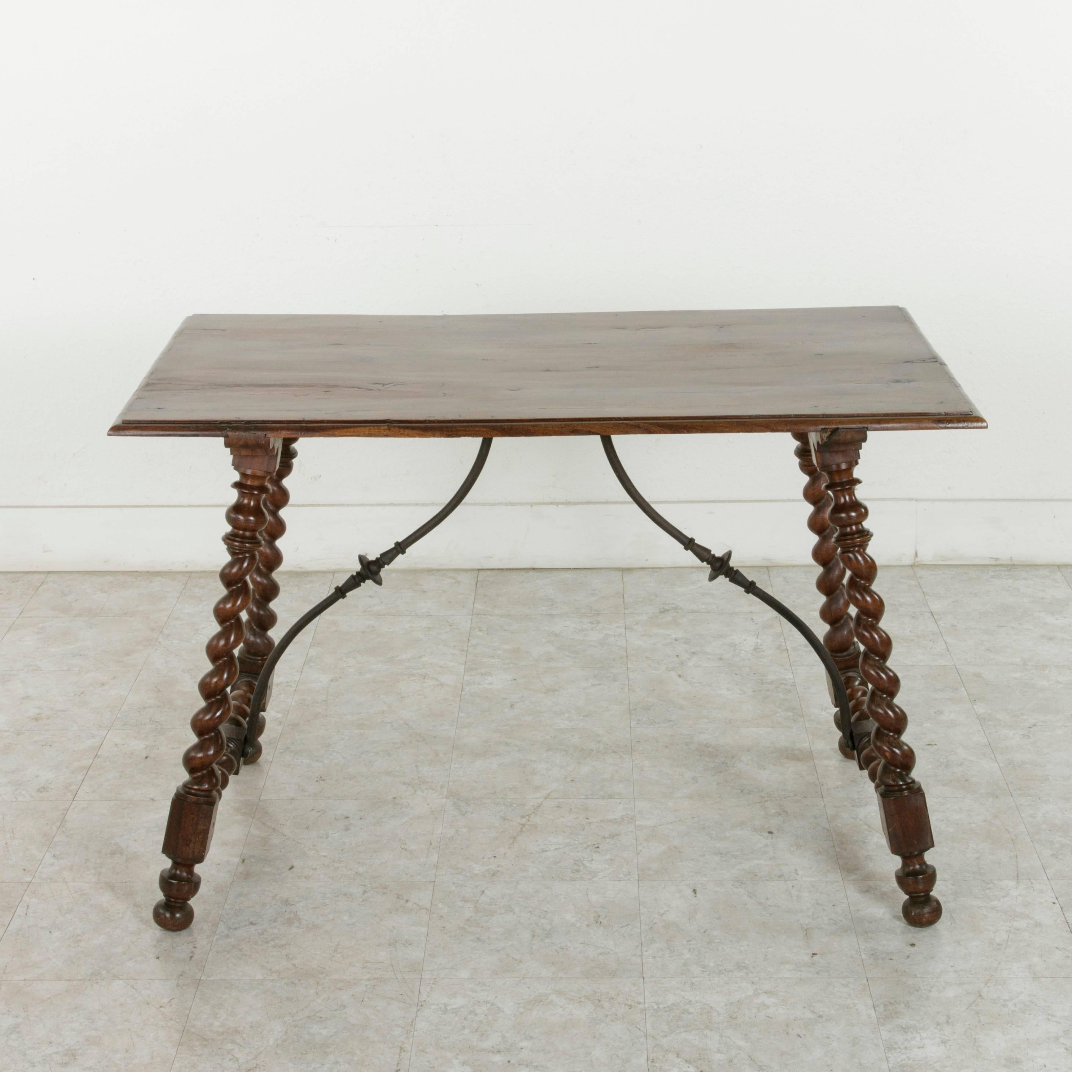 This 19th century walnut table from France features a beveled top supported by Classic barley twist legs. Barley twist stretchers between the hand pegged lower die joints of the legs support hand-forged iron braces that attach to the top providing