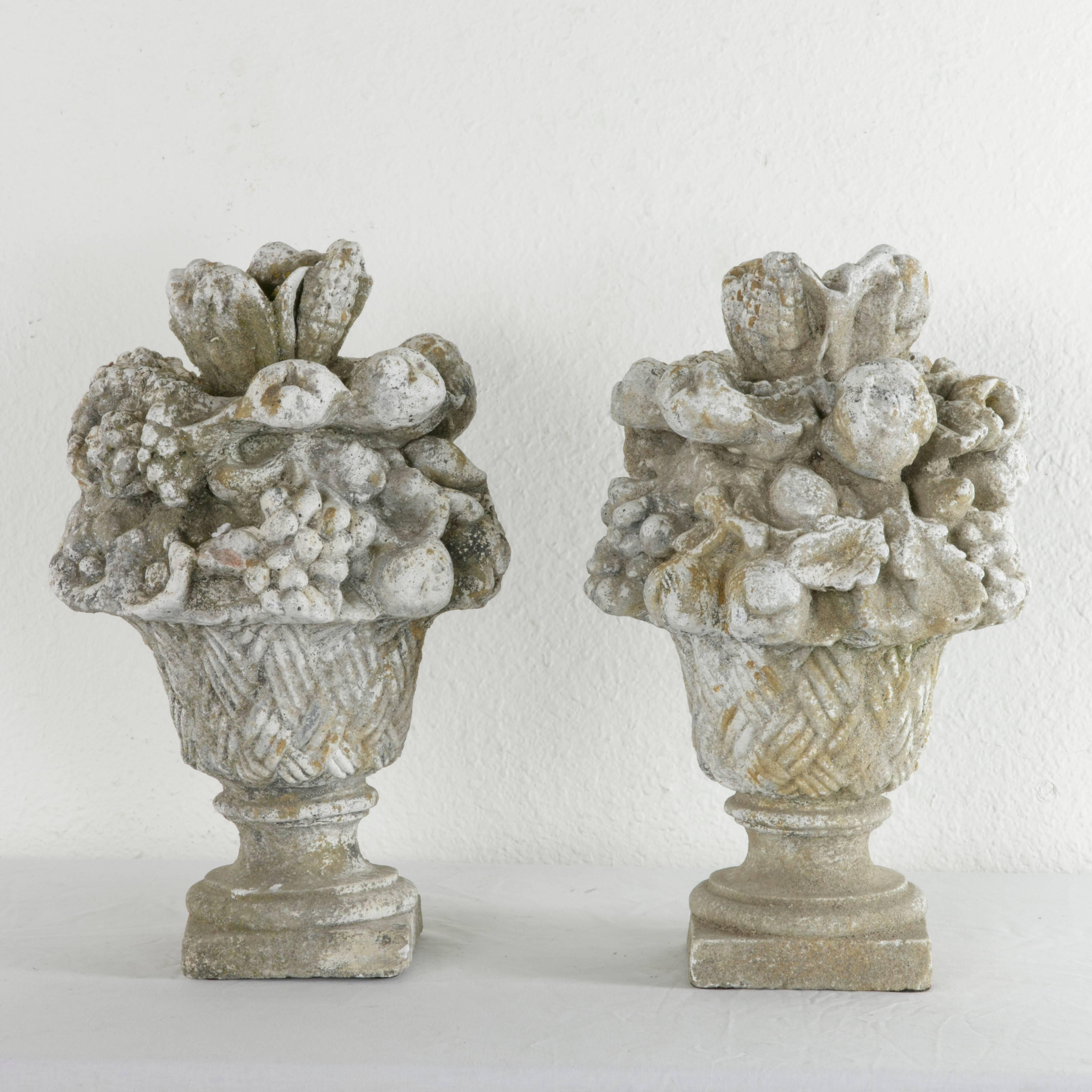 This pair of early 20th century French cast stone sculptures features an abundant bouquet of fruit artfully arranged in a woven basket. Vestiges of lichen and moss as well as a weathered patina are evidence of its former setting in a Normandy