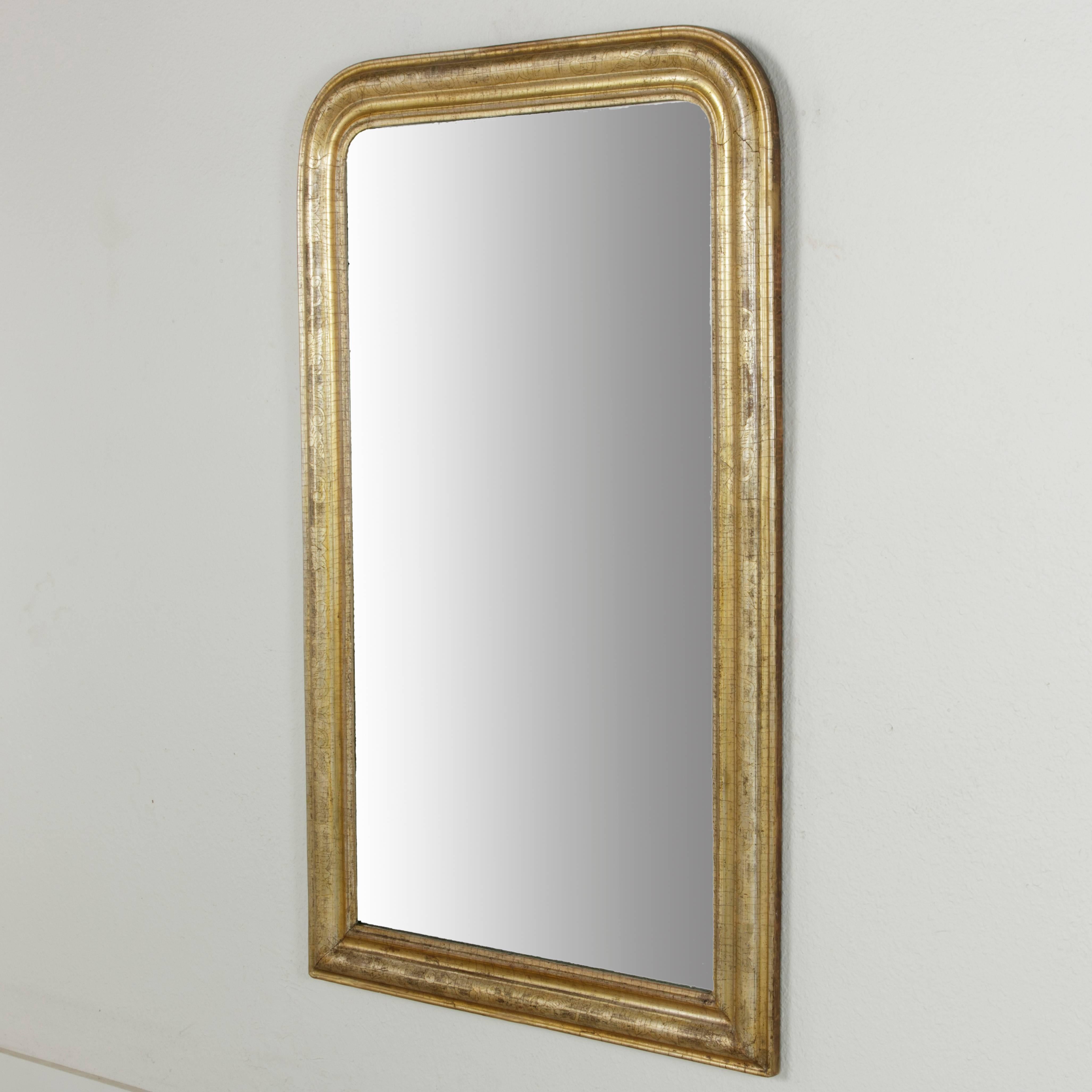 This nineteenth century French Louis Philippe period mirror is set apart from the rest by its amazing patina! Its incised gilt wood frame has aged in such a way that silver highlights appear in the gilding. With dimensions of 54 inches in height and