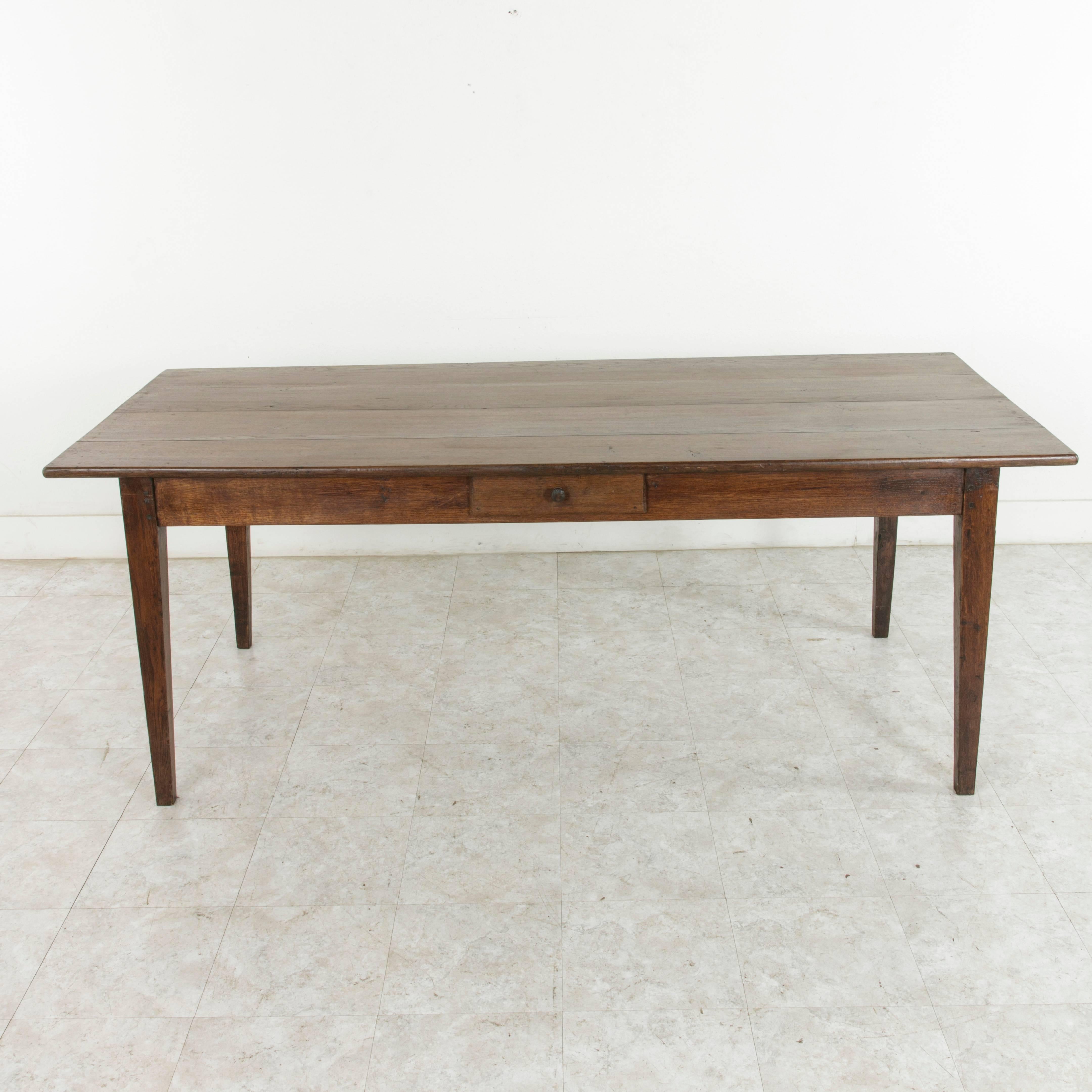 Originating from the region of Le Perche, a sub-region of Normandy France, this artisan-made, hand pegged oak farm table or dining table dates to the turn of the twentieth century. Its top is constructed of four wide planks and rests on tapered