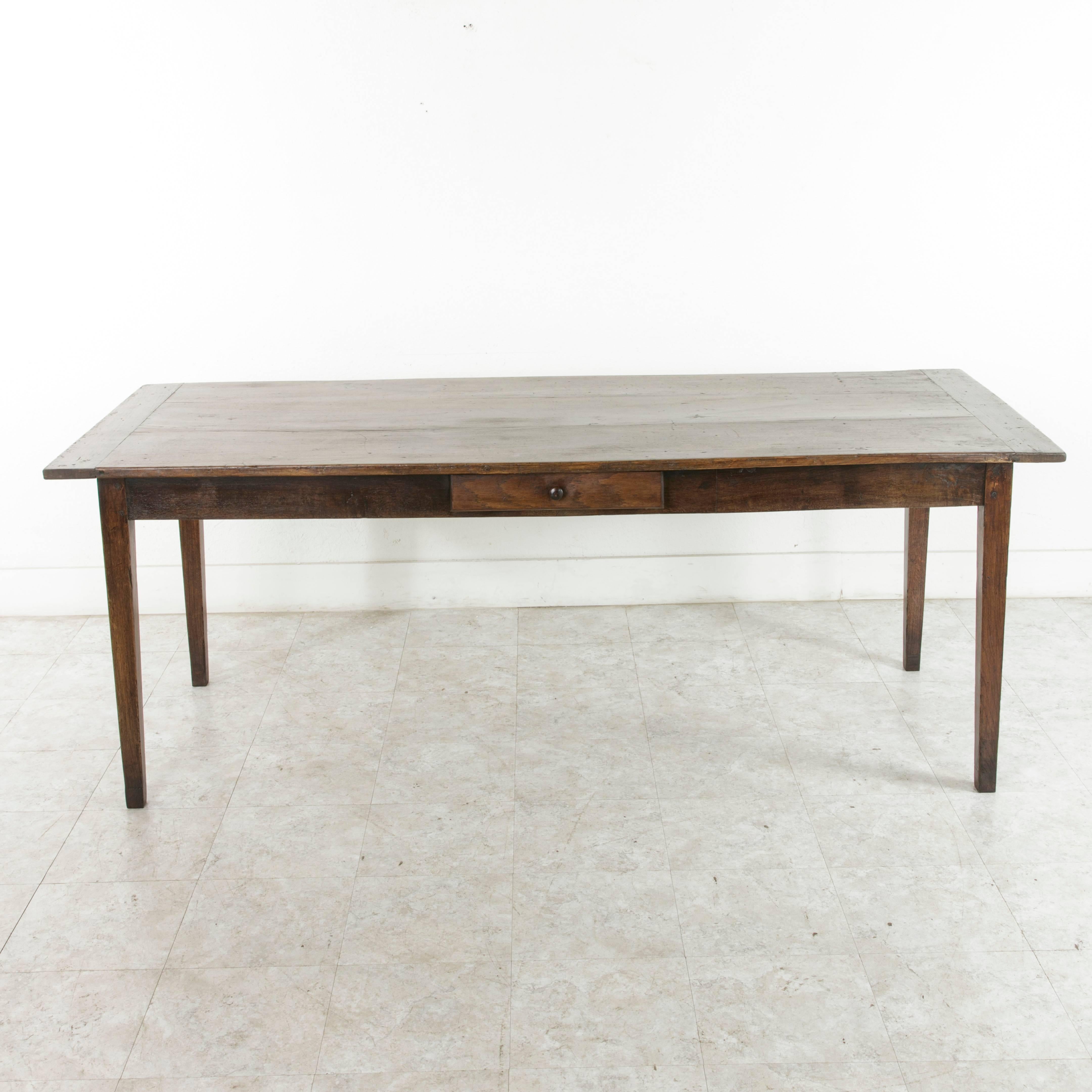 This artisan-made hand pegged poplar farm table or dining table is from Le Perche, a Sub-region of Normandy, France. Its top is constructed of three wide planks and rests on gently tapered legs. Its single drawer on one side was originally used to
