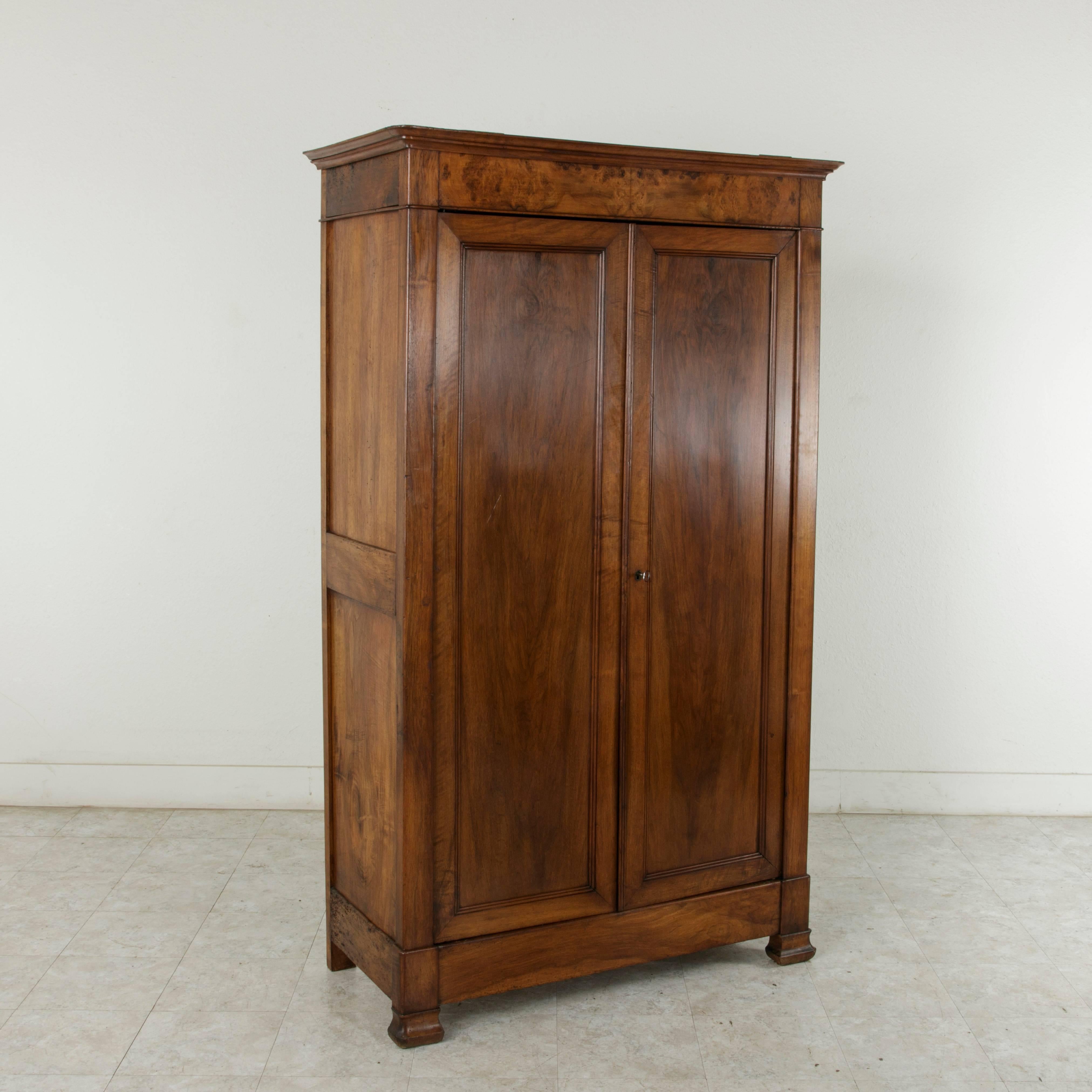 Found in the region of Brittany, France, this small-scale mid-nineteenth century walnut armoire features simple clean lines, the Classic distinction of the Louis Philippe style. A period piece, its solid panelled sides and doors glow with the rich