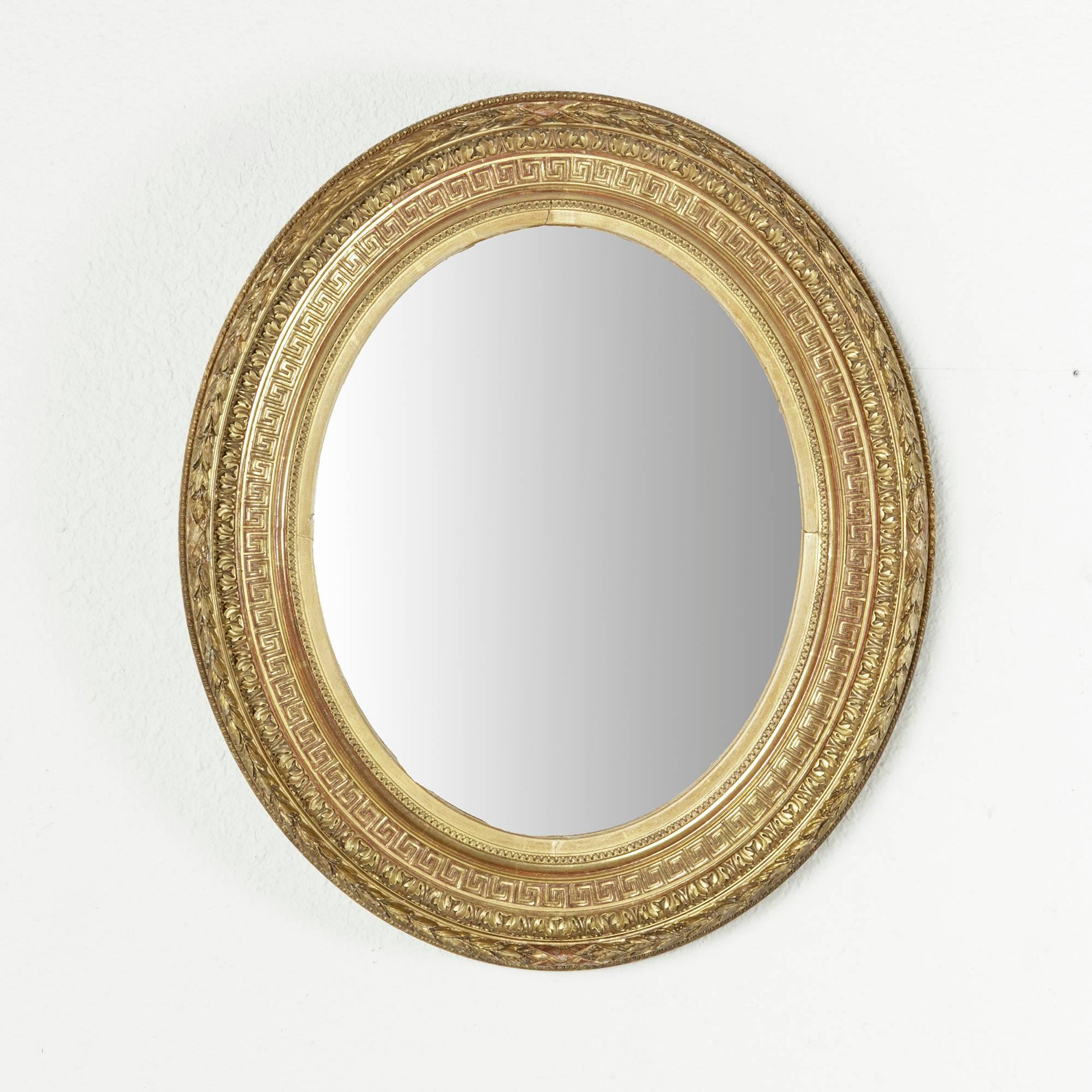 This exquisite small-scale Napoleon III period gilt oval mirror features multiple bands of Louis XVI detailing including acanthus leaf and Greek key motifs. Of a rare small-scale, this mirror would be ideal for a powder bath or small entryway. c.