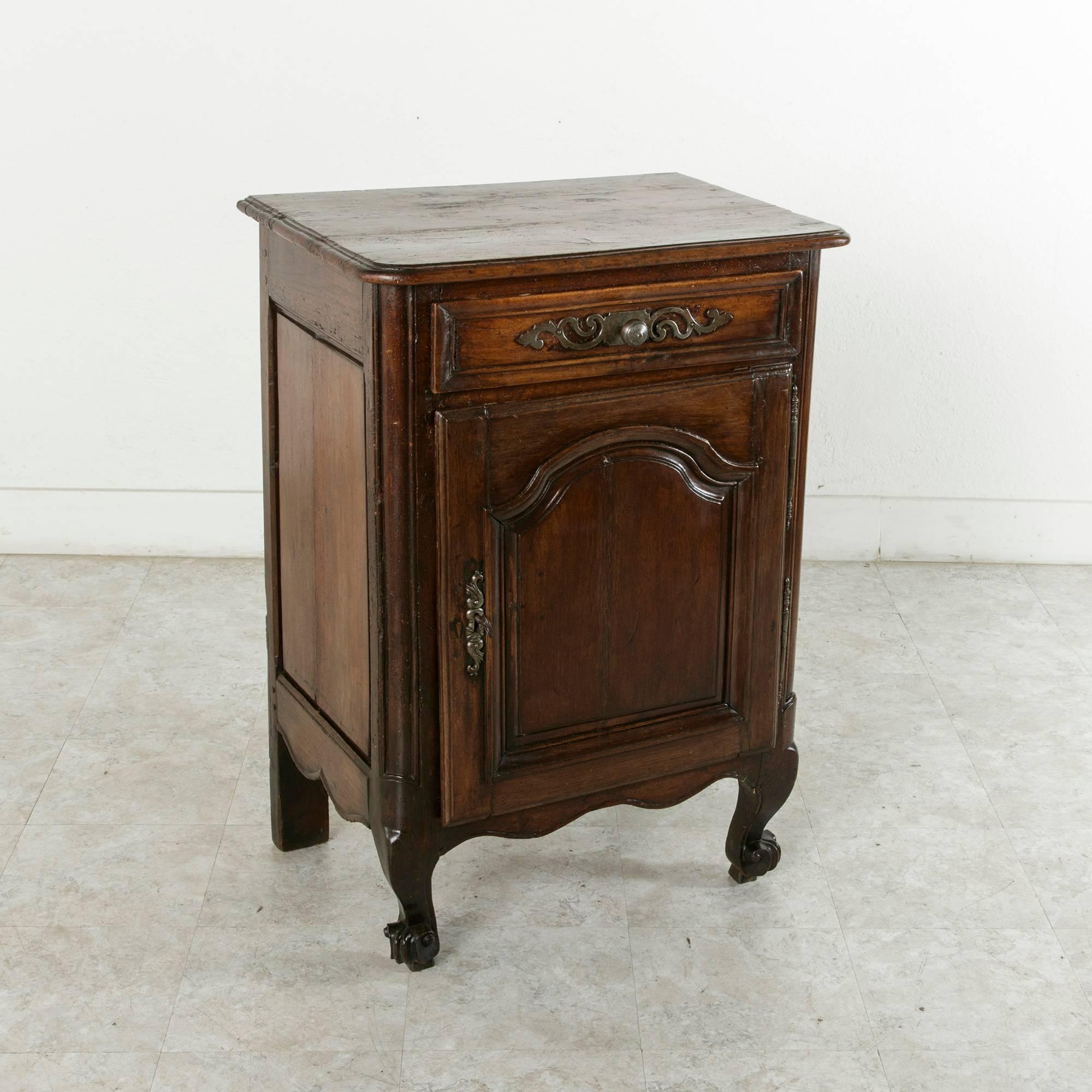 This 18th century hand-carved oak jam cabinet boasts its original lock and key and iron hardware. A transition piece combining two styles, this cabinet features a Louis XIV door with a symmetrical curved panel and Louis XV cabriole legs ending in