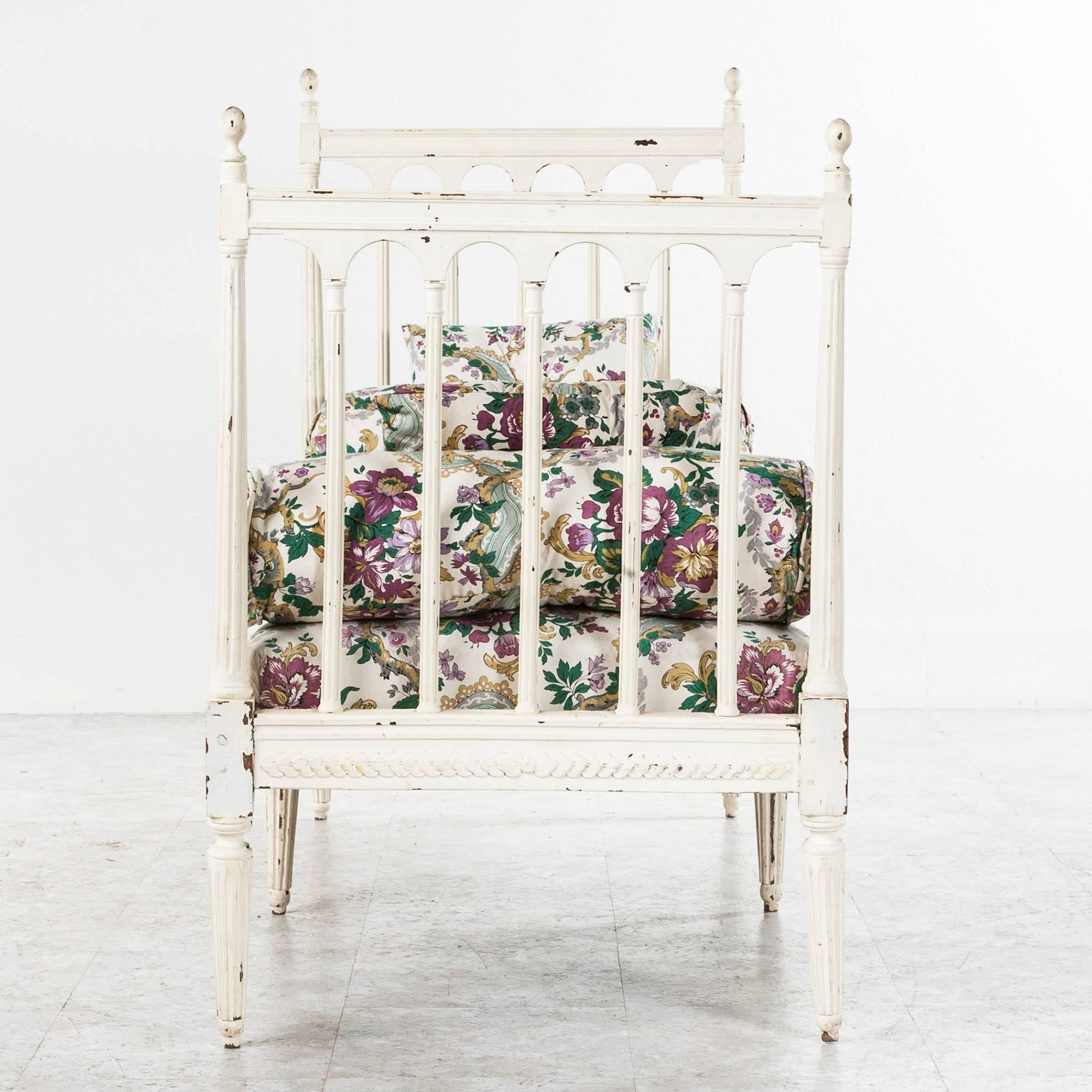 This charming painted Louis XVI style daybed or child's bed circa 1920 came out of a home in Versailles. The high straight sides are reminiscent of the Swedish Gustavian Style, but the playful floral upholstery is quintessential French. This piece