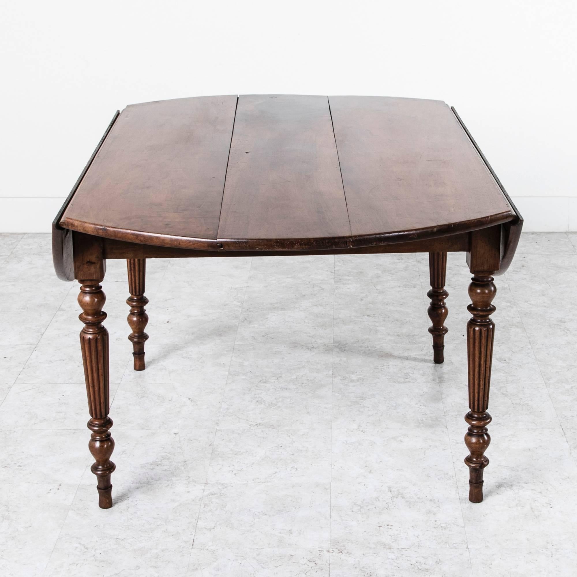 This elegant dining table features narrow turned and fluted solid walnut legs. Created in early 19th century France, this piece's style and construction have stood the test of time. It will sit six comfortably for dining and conversation while