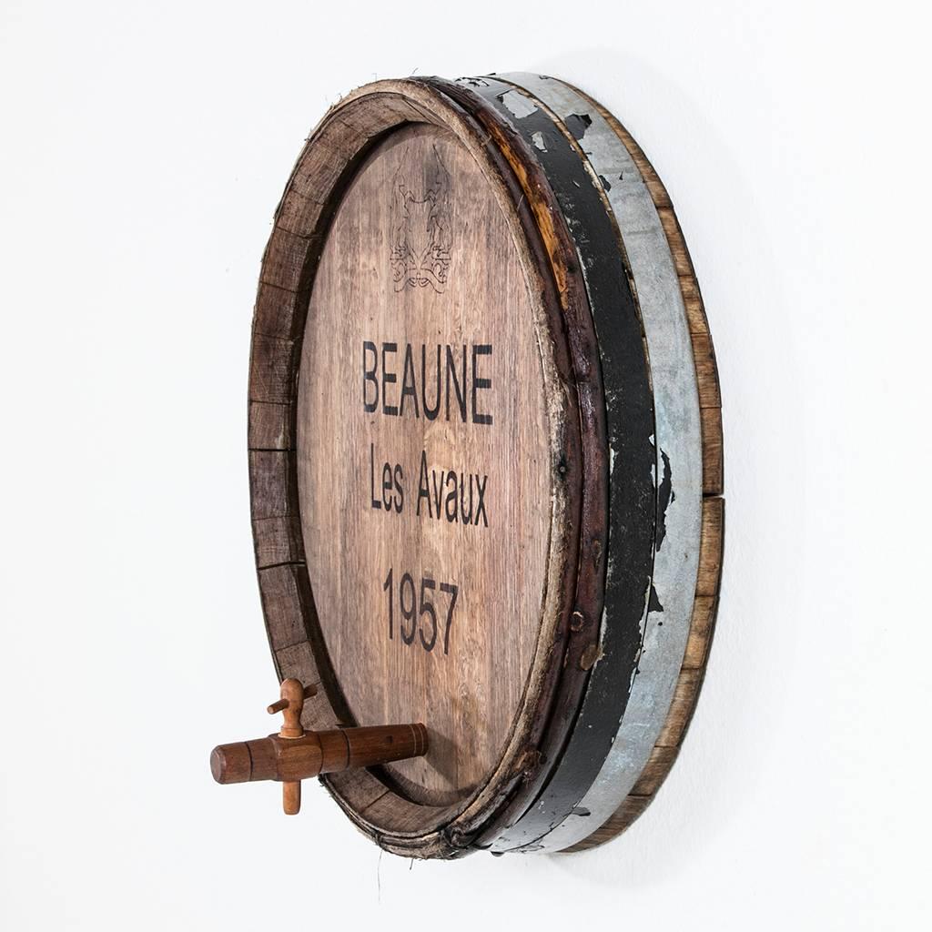 The perfect wall decor for any wine cellar, this Burgundy wine cask front features its original iron straps and tap. Marked with the name of the wine, Beaune Les Avaux and the year of its vintage 1957. Two other wine barrel tops, Pommard La Combotte
