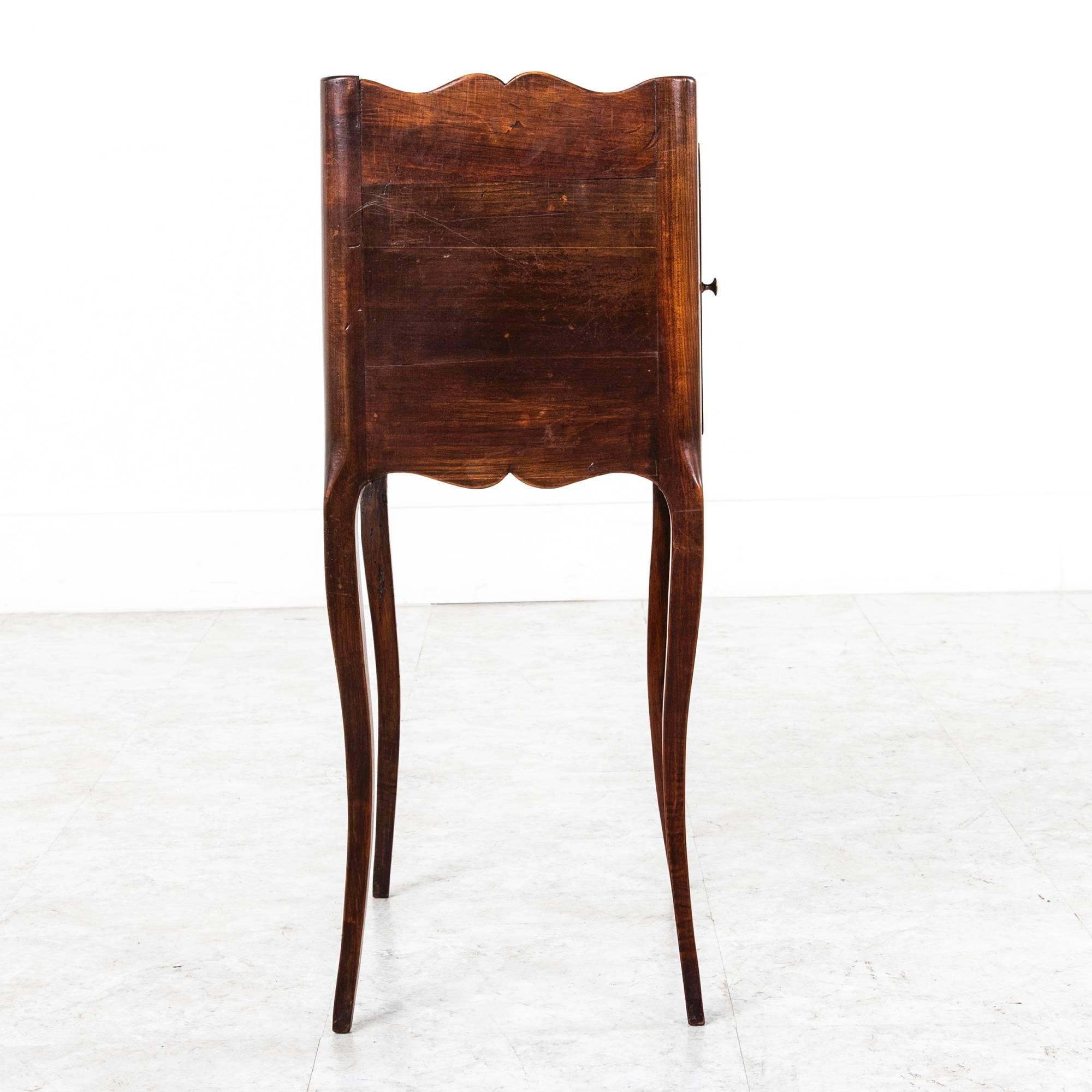This unusual, hand-carved walnut nightstand from Provence has elegant elongated cabriole legs and a simple profile. A classical hand-carved urn adorns its solid walnut door. Finished on all sides, this piece can be placed in the middle of a room and