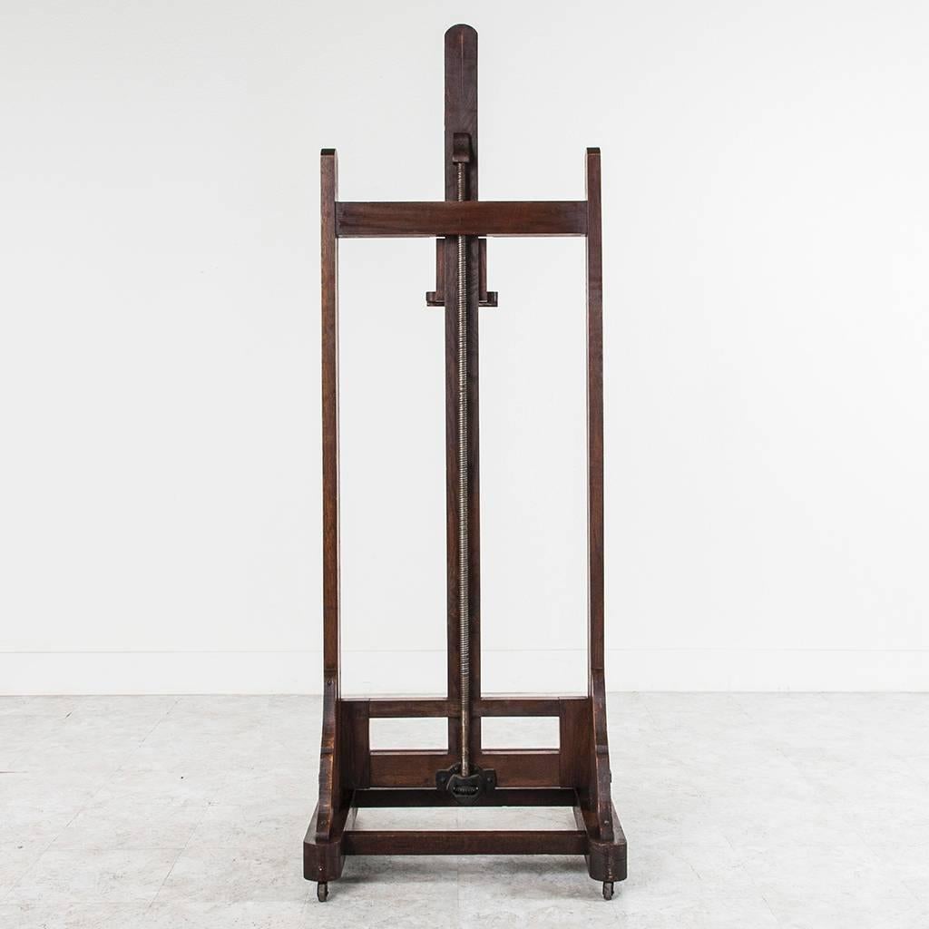 This grand late 19th century oak artist's easel has its original functioning crank mechanism to adjust the tray height. With a clever extendable notched catch at the top for multiples or deep edge canvases, this easel can handle impressively large