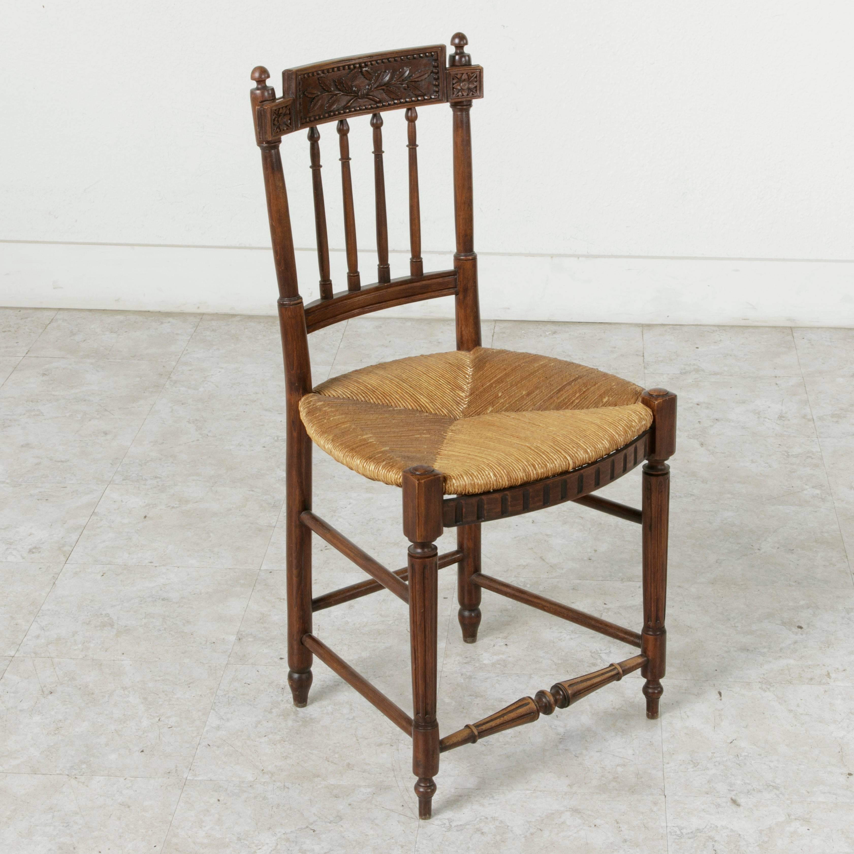 This lovely set of four hand-carved walnut chairs boasts a unique transitional rustic Directoire style. The rush seats are quite comfortable and surprisingly intact and supple considering their age. The petite scale of these chairs would allow them