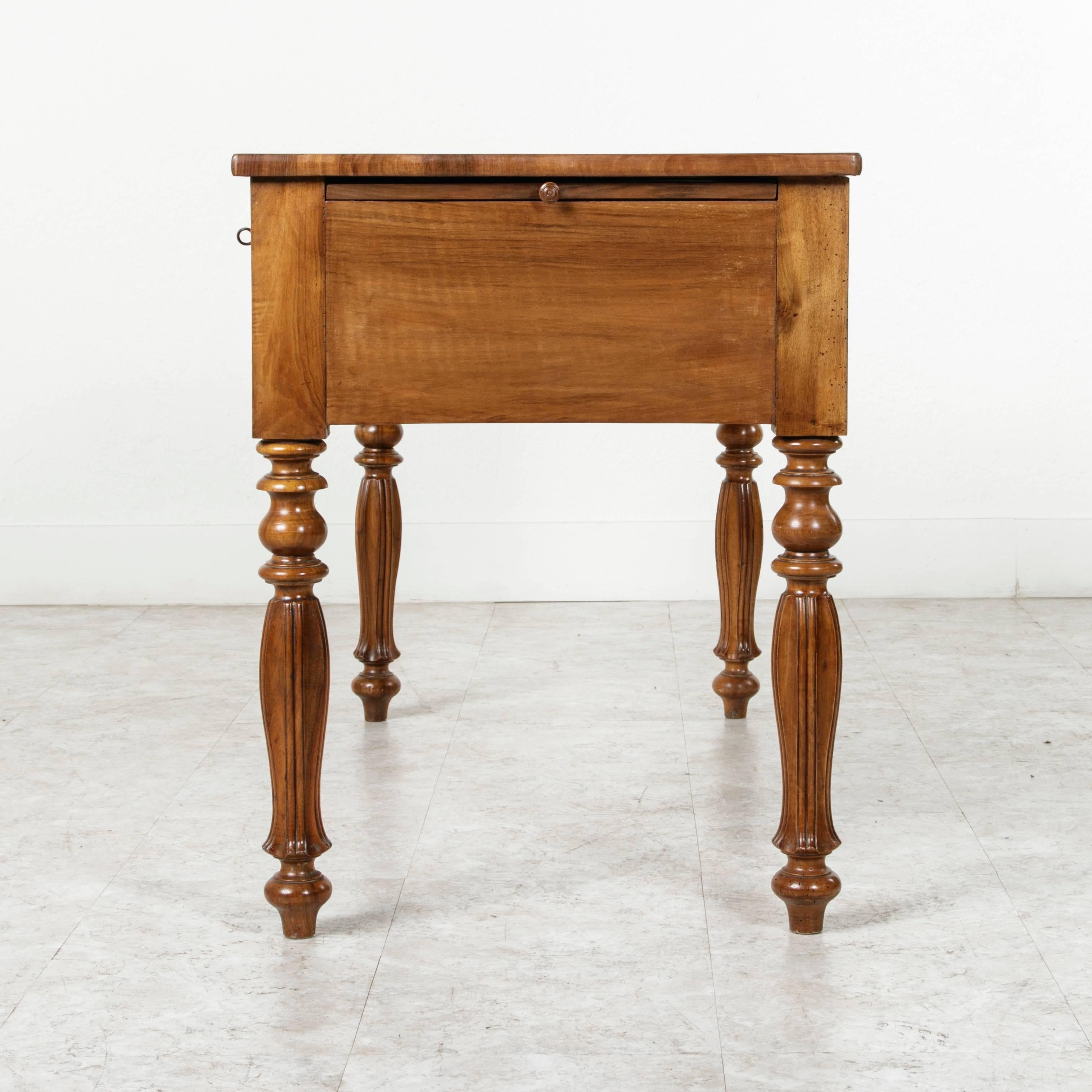 This Louis Philippe period desk is made of eye catching bookmatched burl walnut and stands on unusual turned 
