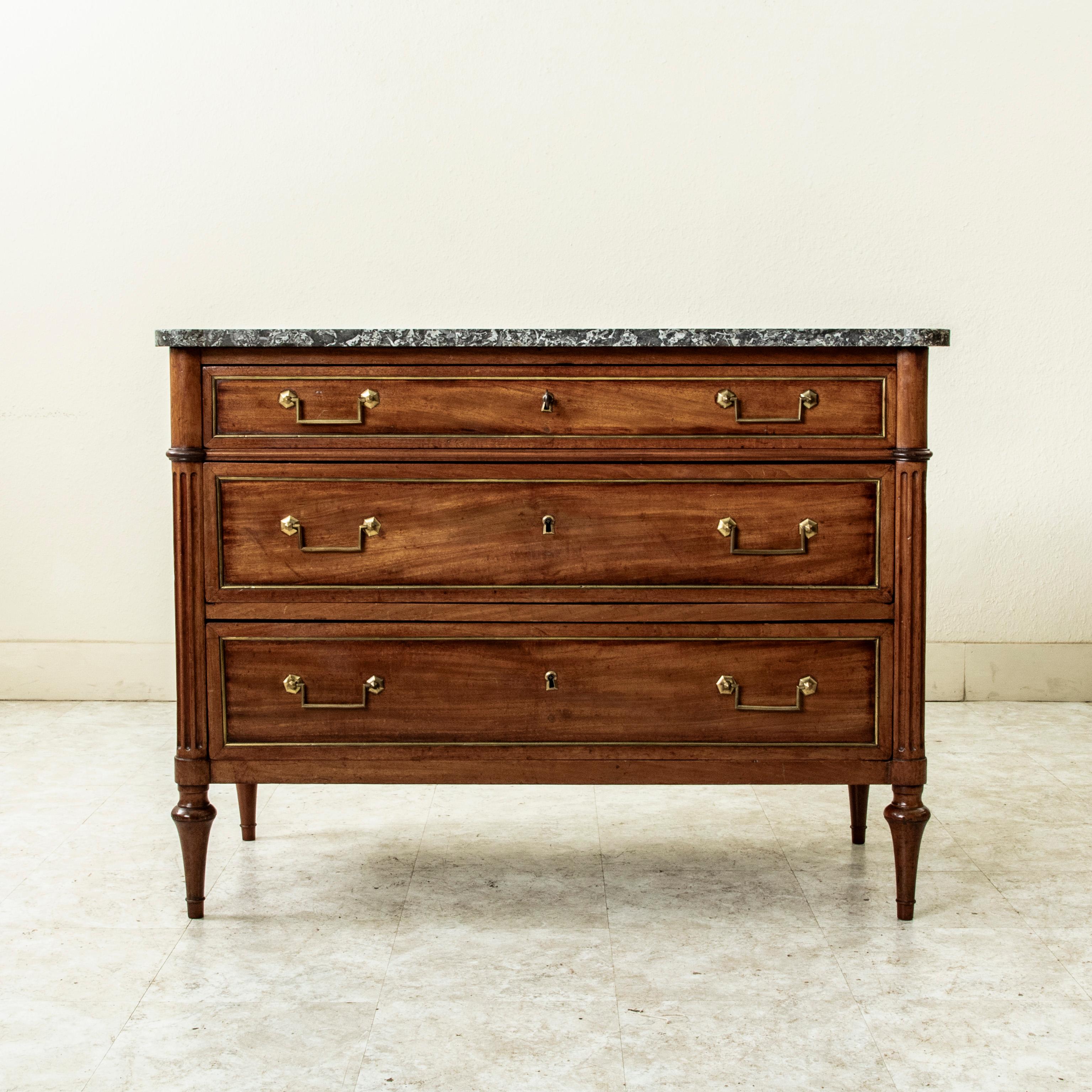Cette commode ou commode en acajou de style Louis XVI français du XIXe siècle présente un plateau en marbre Sainte-Anne biseauté et des coins arrondis et cannelés. Ses trois tiroirs, construits en queue d'aronde, sont dotés de poignées de tiroir