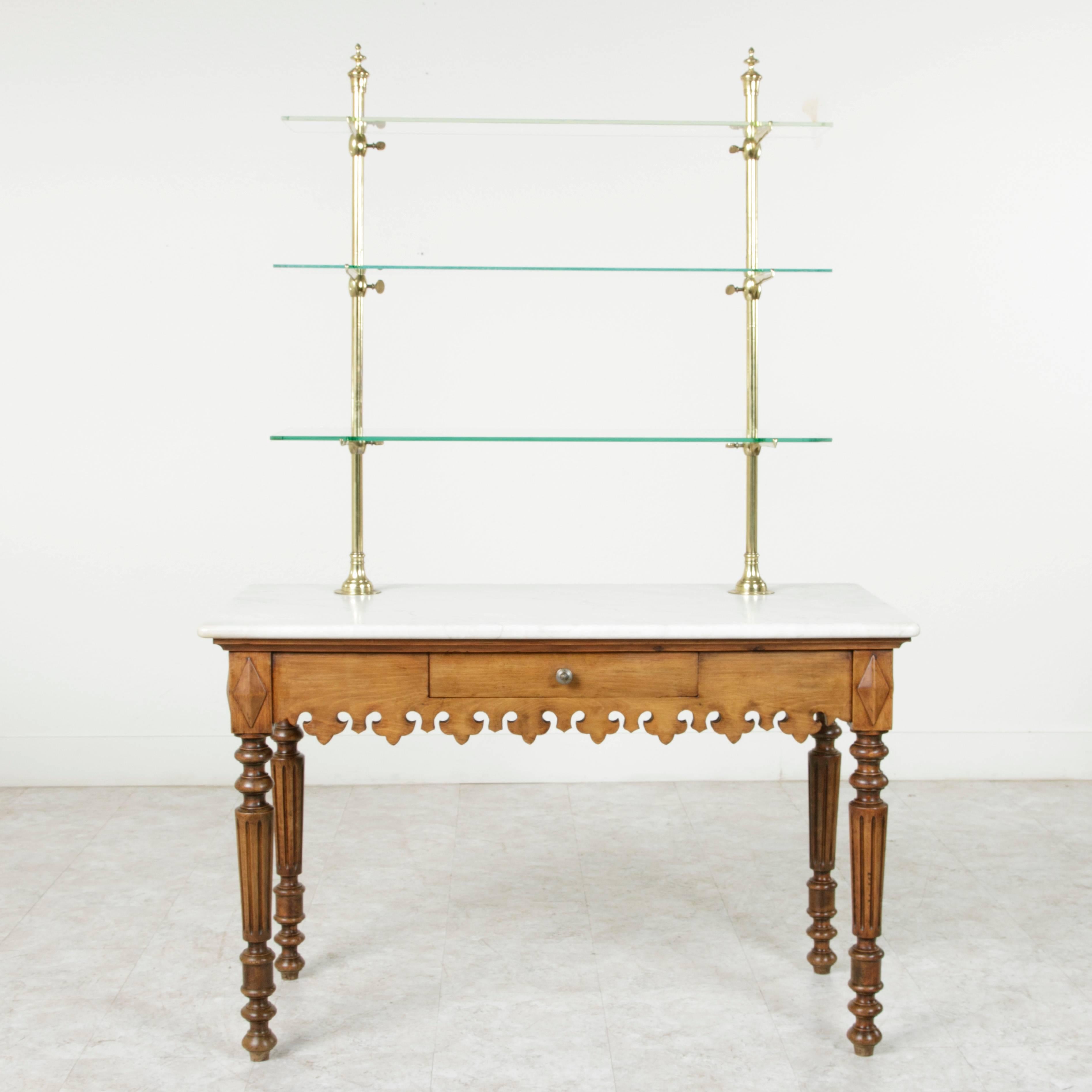 An extremely rare find, this airy and entirely unique pastry table etagere will make an impressive showcase in a kitchen, pantry, or shop space. The table is constructed of heart pine with finely turned and fluted legs beneath a pierced Fleur de Lys