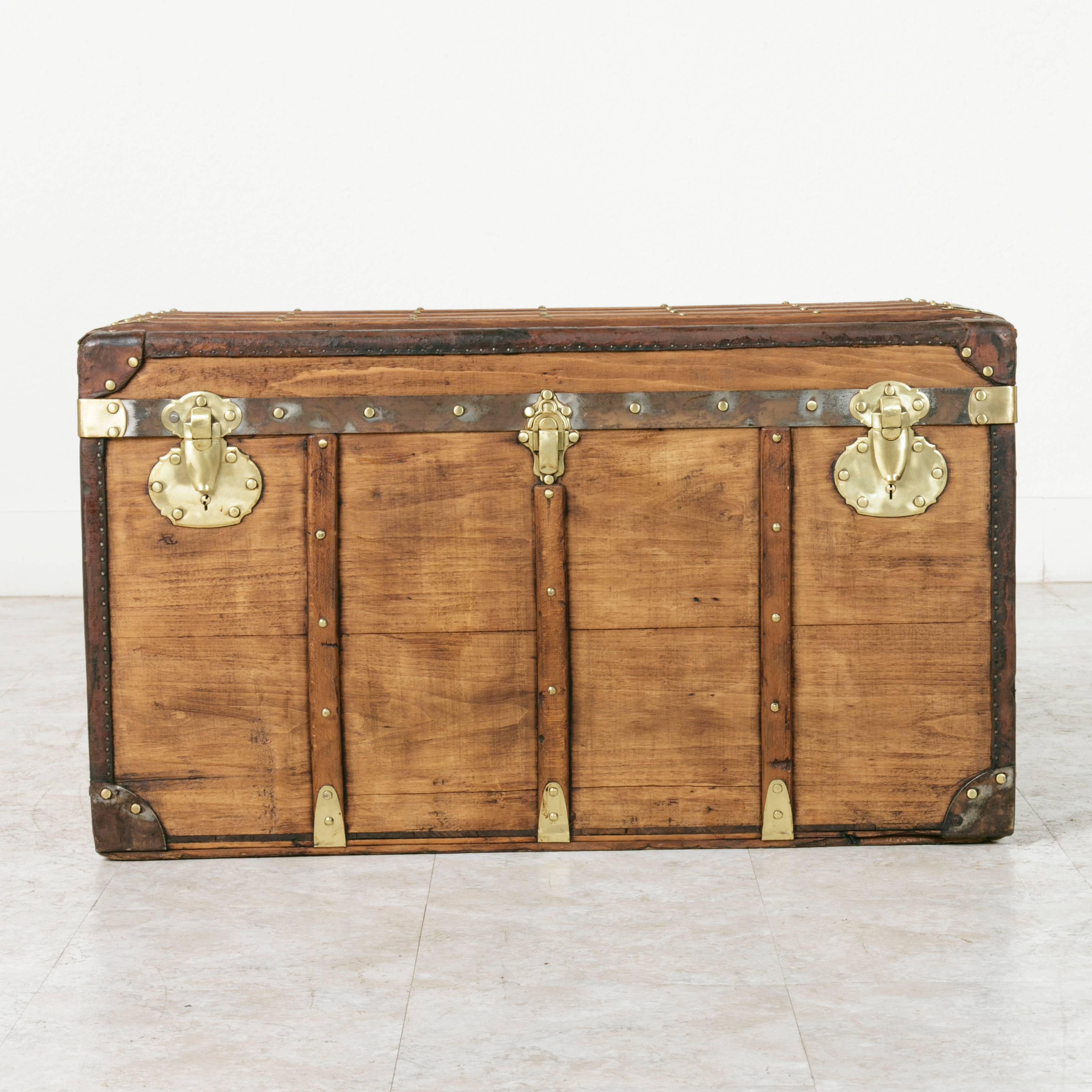 This early 20th century steam trunk features many sought after details. Its flat top makes it an excellent choice for use as a coffee table or side table, and its polished brass and iron trimmings give it a flash of luxury. This piece is made of