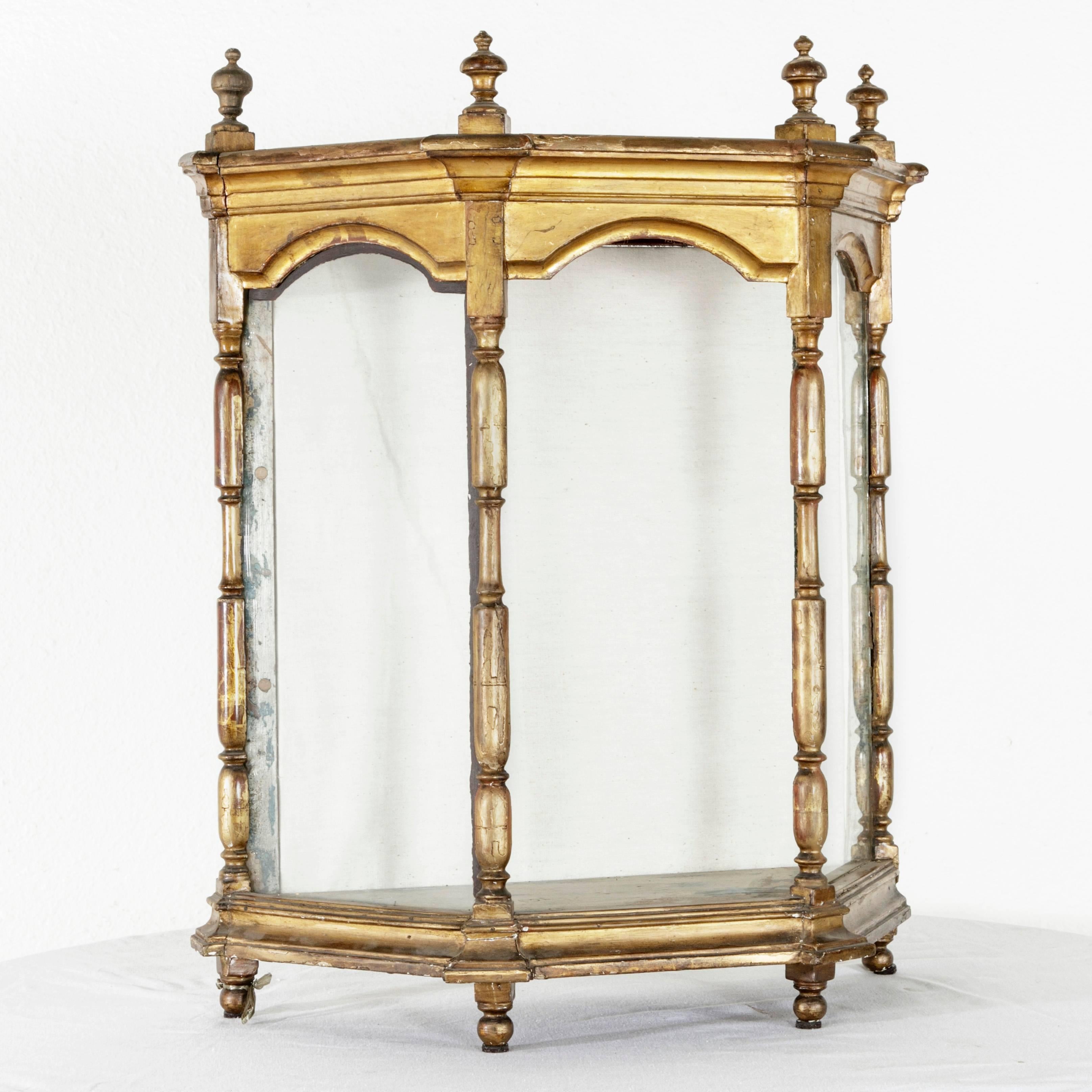 This 19th century giltwood vitrine originally hails from a French church in the Ile de France region where it originally displayed a small religious statue. Its flat back allows it to be hung upon the wall while its four ball feet support it when