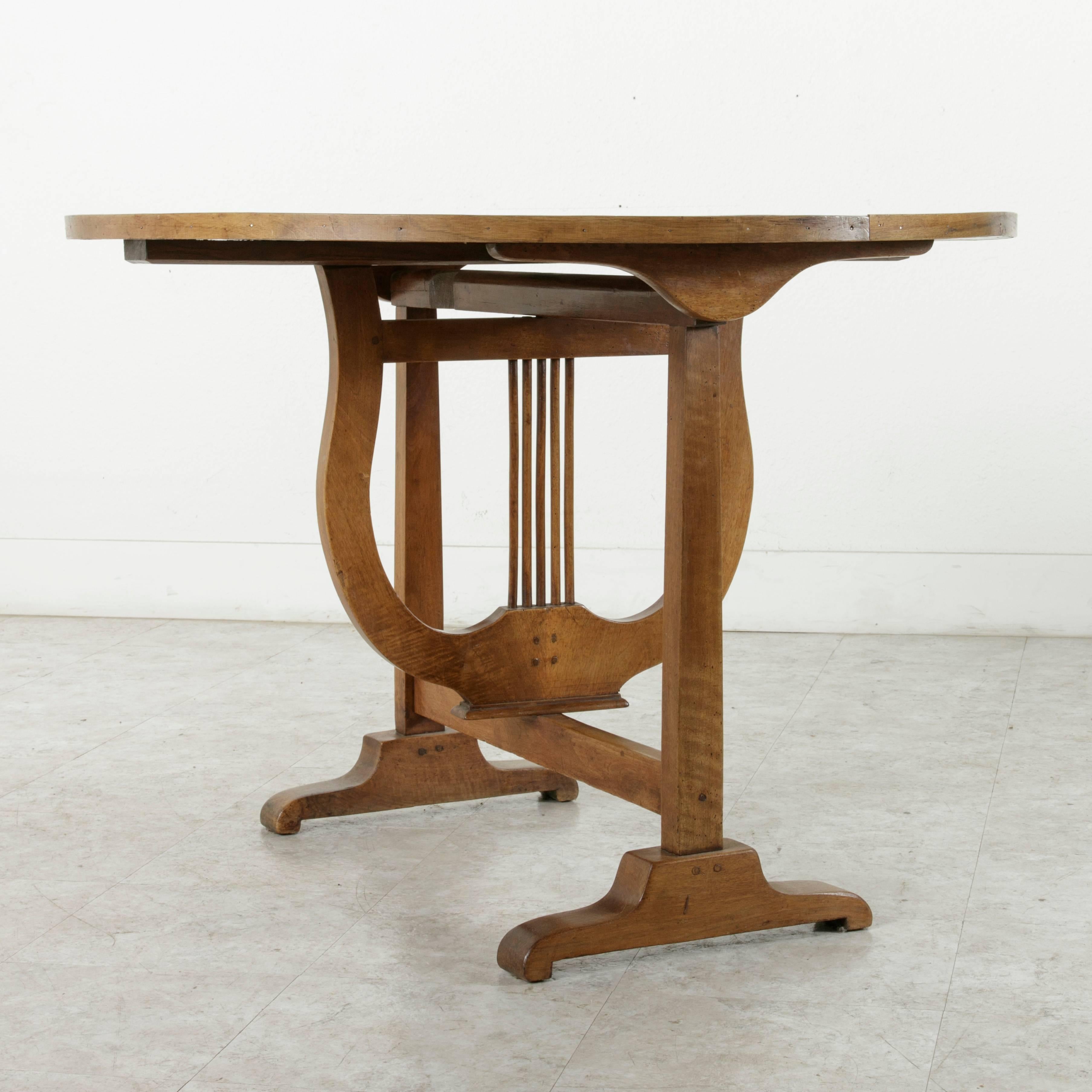 This antique vineyard table was found in Dijon, in the heart of the Burgundy region in France. Constructed of hand pegged walnut, this vineyard table features a swiveling lyre base and pine tilt-top. This piece was originally used for wine tasting
