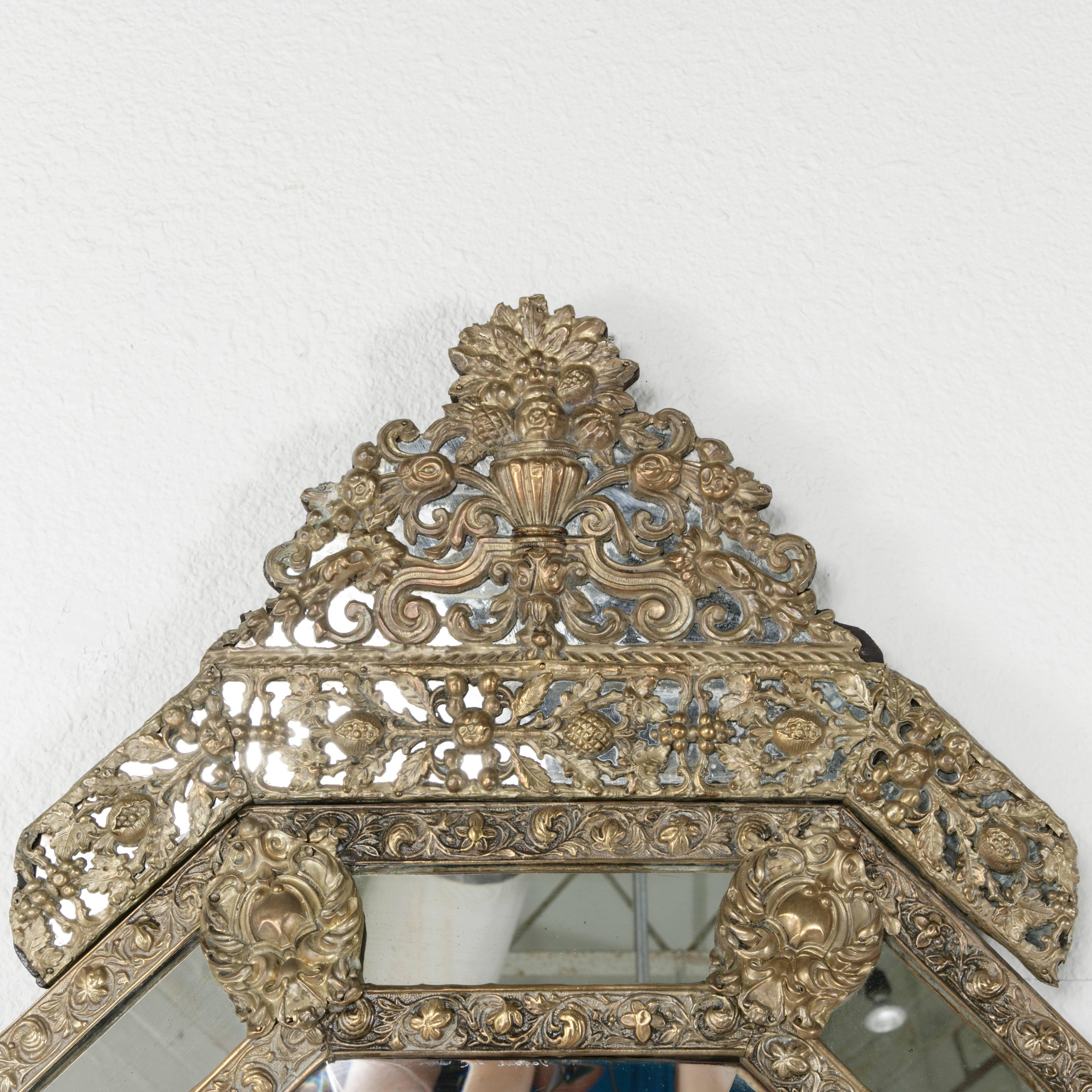 This richly detailed Napoleon III bronze repoussé cushion mirror has a beautifully patinated finish on its floral motif double frame. The original aged mirror insets on this piece lend additional warmth, while the central beveled piece of mirror