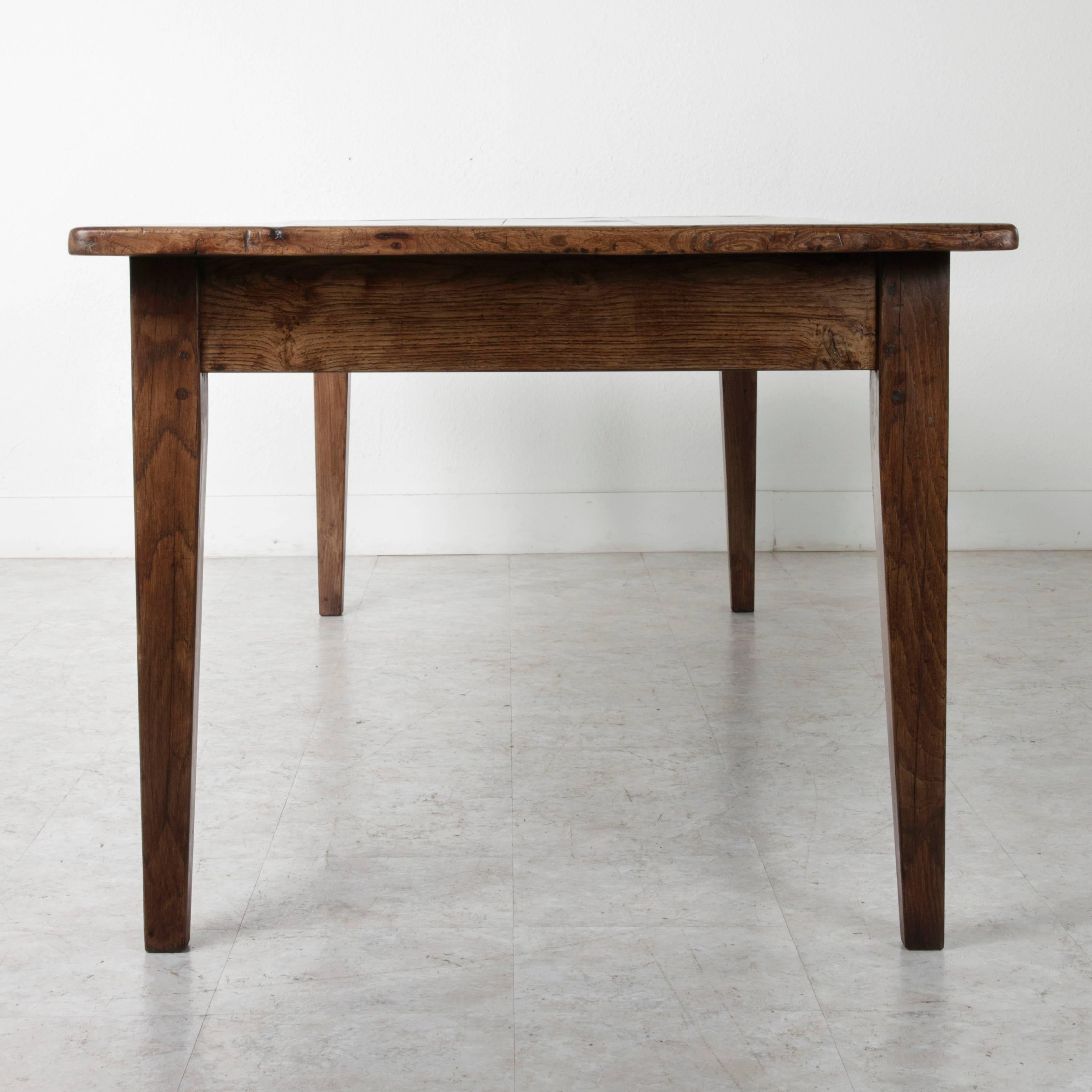 This artisan made farm table's base is made of solid hand pegged French oak, while its top is of solid elm. A simple drawer on one side was designed to hold bread knives at the table, while the other side holds a pull out cutting board. This piece's