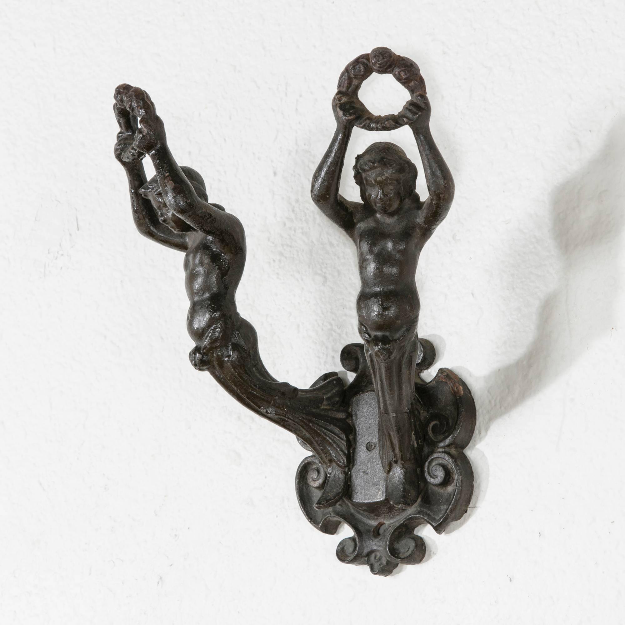 The French Art Nouveau movement brought sweeping changes to the decorative arts of the early 20th century. This cast iron hook of the period unites function and form in two heraldic figures with outstretched arms bearing laurel wreaths. Of a large