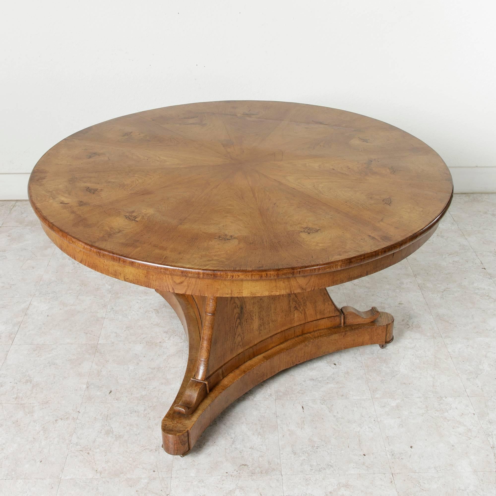 This grand entry table is a rare piece from the short Charles X period in French furniture making. Made of elmwood, this large gueridon features a book matched top that rests on a triangular pedestal base. Its 48-inch diameter hinged top tilts to a