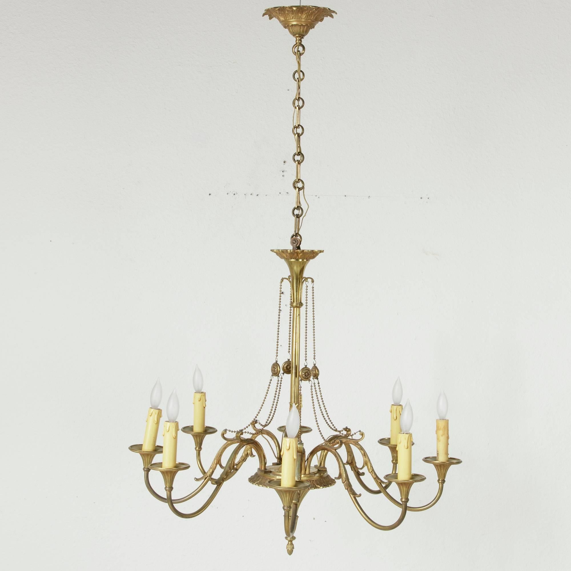 Mid-Century Modern meets Louis XVI in this large-scale bronze chandelier from Versailles. Eight gracefully curved arms detailed with acanthus leaves surround a central column festooned with delicate beading. The acanthus leaf motif is repeated in