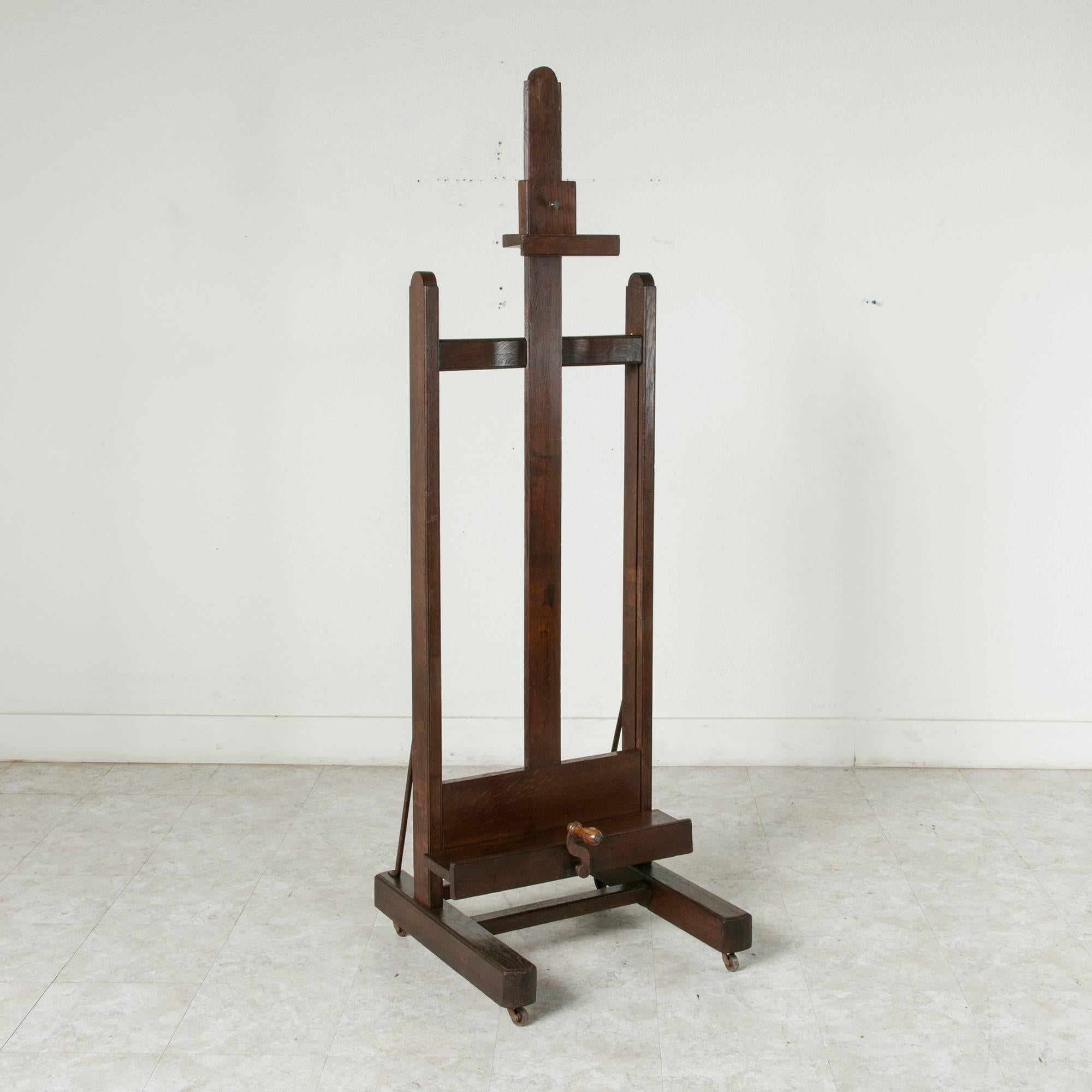 This grand late 19th century oak artist's easel has its original functioning crank mechanism to adjust the tray height. With a fantastic adjustable height of 69 inches to 105 inches, this sturdy easel can handle impressively large canvases or make
