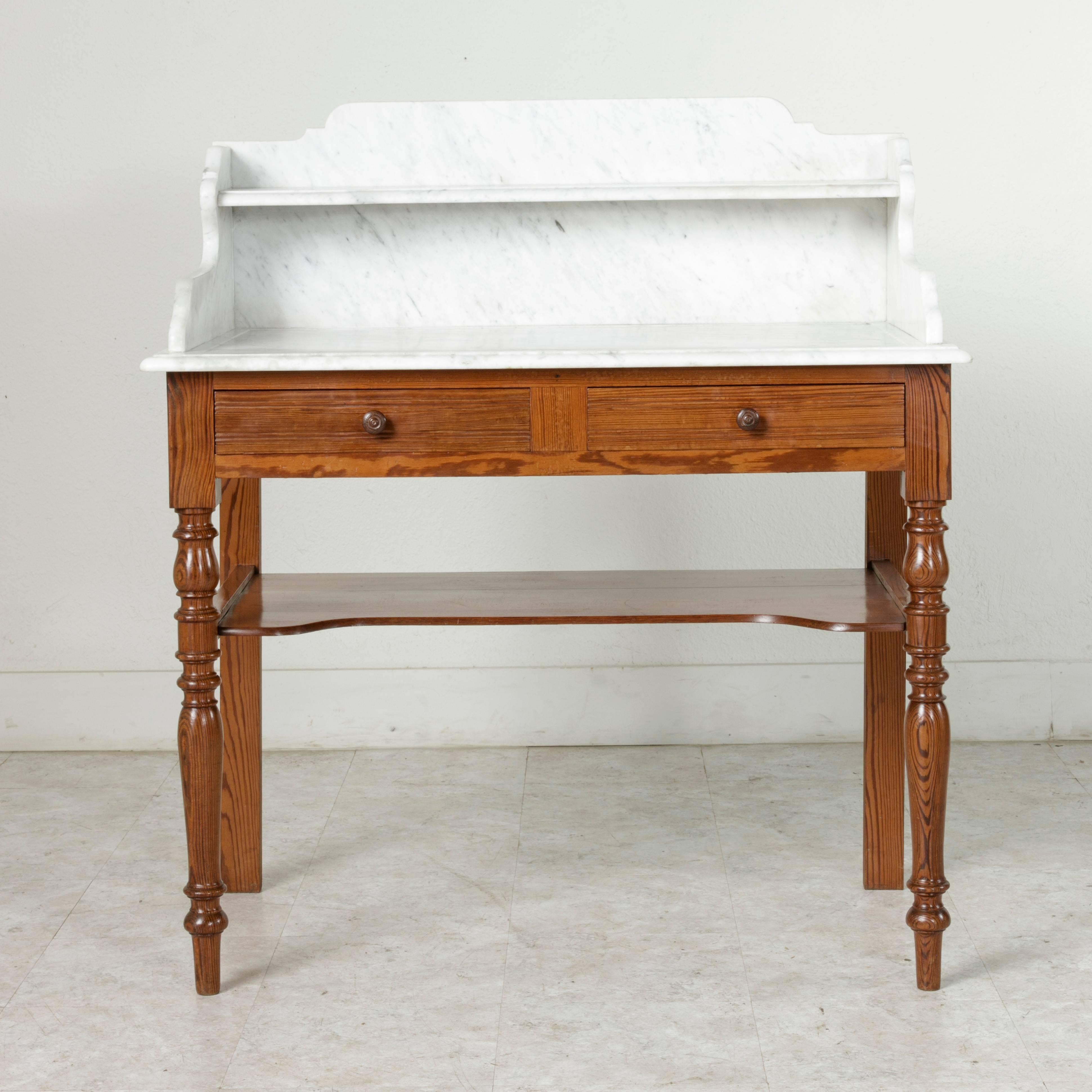 Originally part of the furnishings of a hotel in Bagnoles de l'Orne, a town in Normandy, France famous for its turn of the century therapeutic baths, this early 20th century pitch pine vanity features a beveled Carrara marble top with an upper