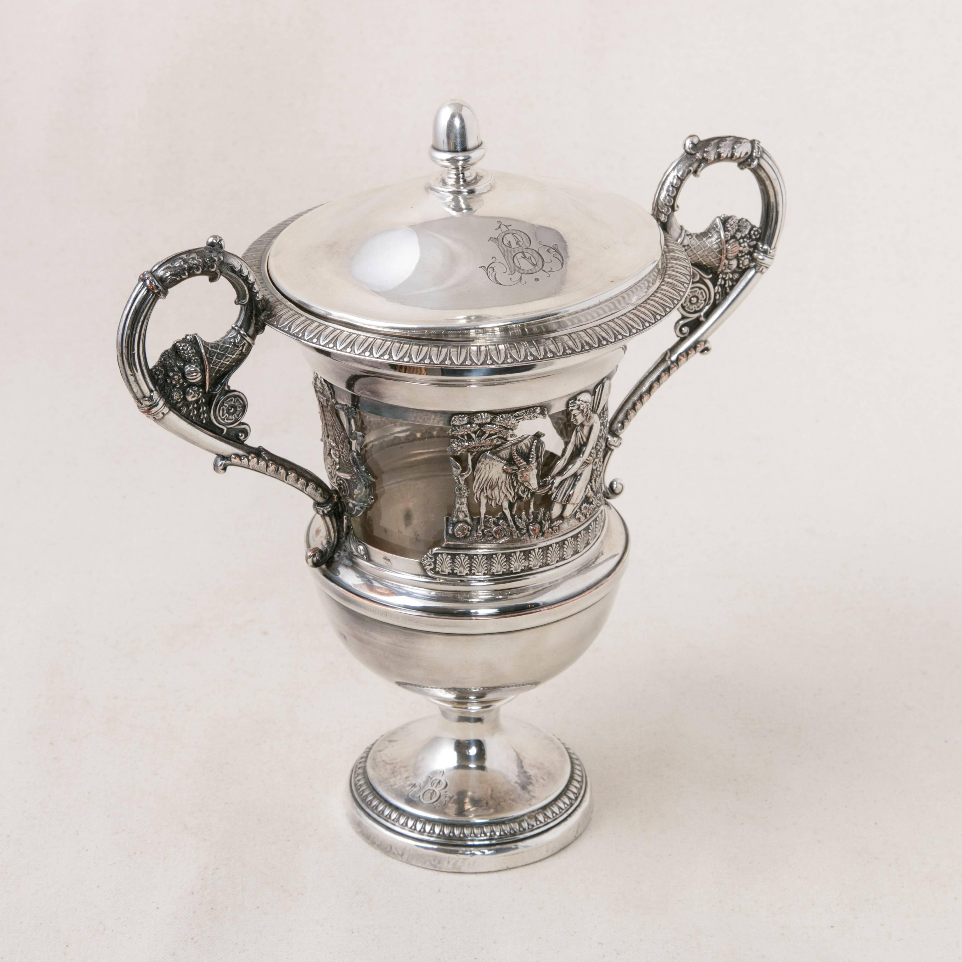 Originally used to present fine jam at tea time, this 19th century, English silver plate serving piece has its original crystal insert and silver lid. Opposing swans with outstretched wings form the sides of a Classic lyre that support two handles