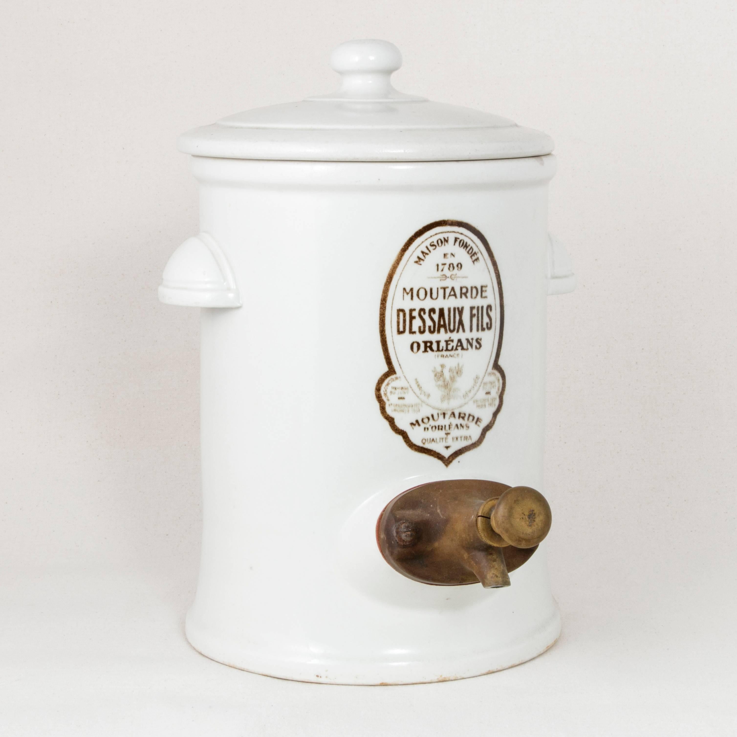 This very large early 20th century white faience mustard pot or dispenser with its lift-off lid features the label of the mustard and vinegar maker, Dessaux Fils, Orleans, founded in 1789. The back is marked as well with the name of the maker.