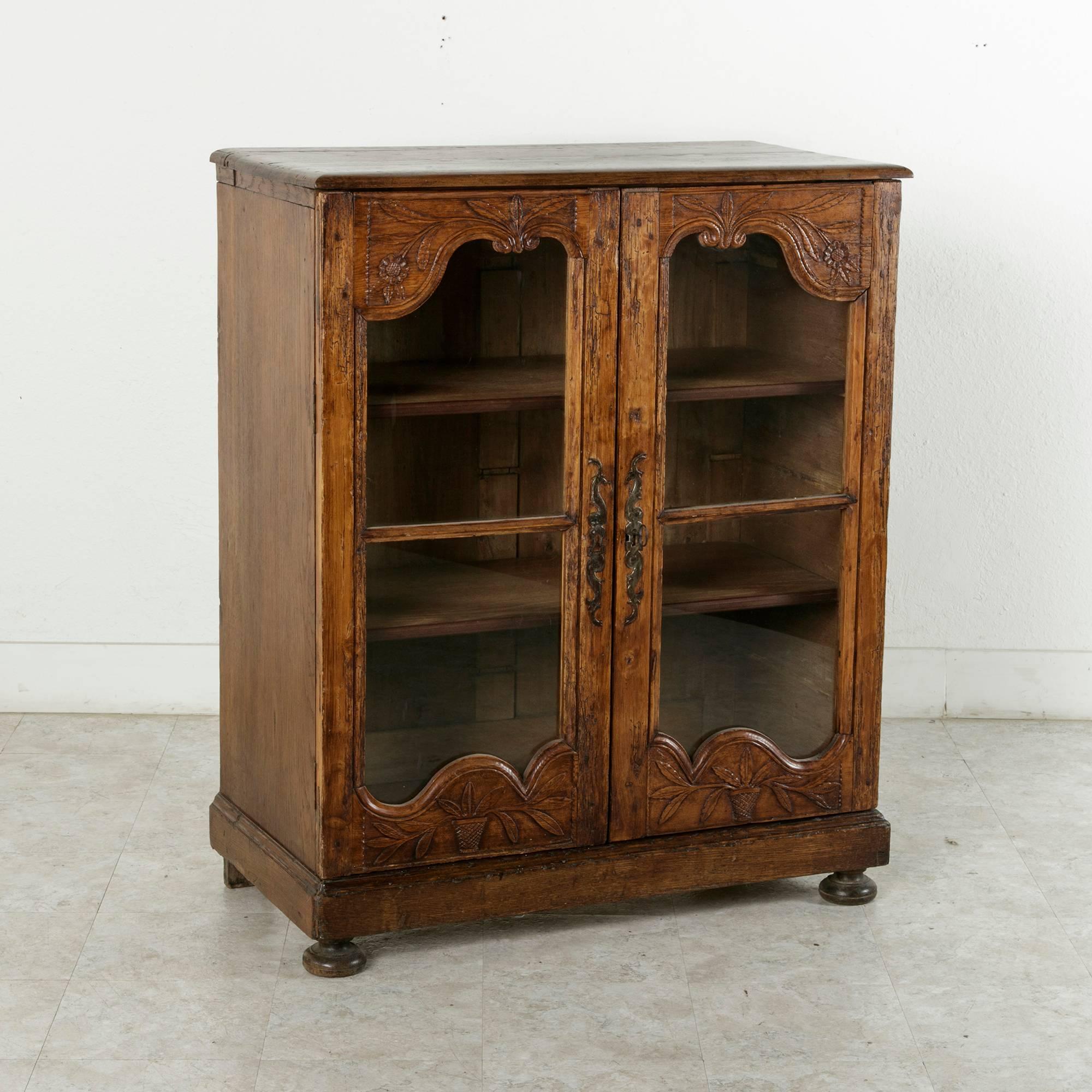 Artisan-made pieces of furniture from the French countryside often were created from a mixture of woods, depending on what was available in the region and on hand. This rustic vitrine features a hand-carved pine facade and an oak cabinet mounted on