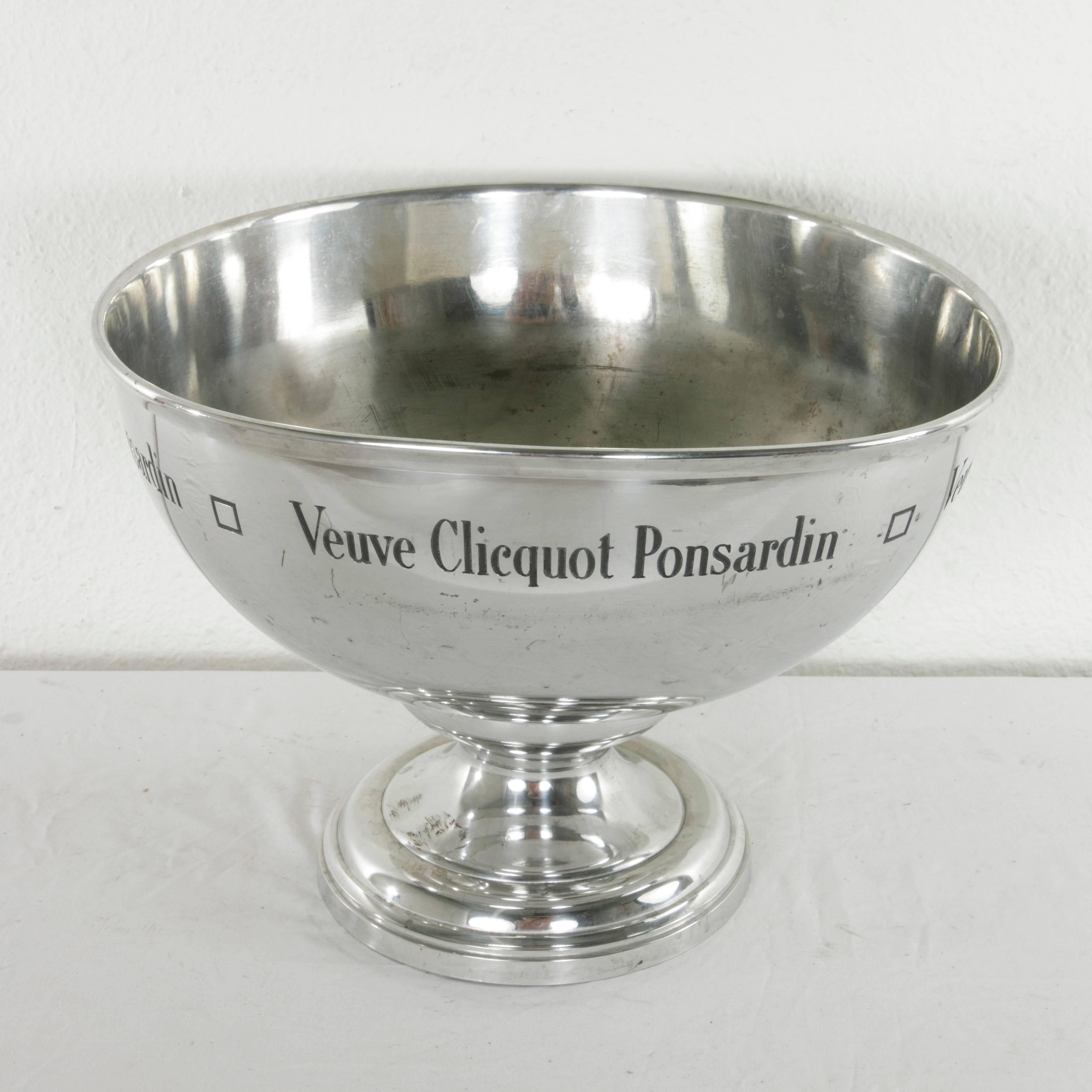 This mid-20th century silver plate over pewter hotel champagne bucket holds four to six bottles and features the name of the renowned champagne producer Veuve Clicquot Ponsardin around the upper rim. Stamped on the bottom by the French fabricator,
