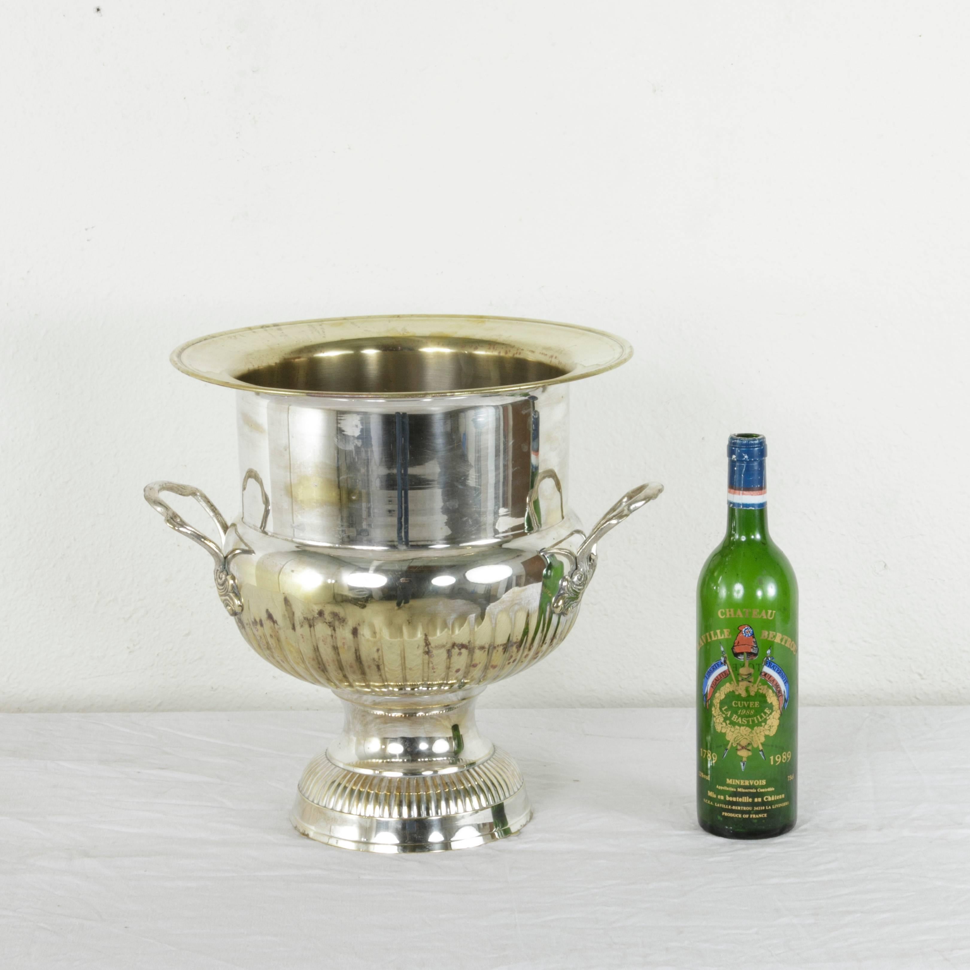 This very large midcentury French hotel champagne bucket in the shape of a Versailles urn stands at an impressive fourteen and a half inches in height and holds up to four bottles. Handles with detailing of leaves adorn each side and allow for