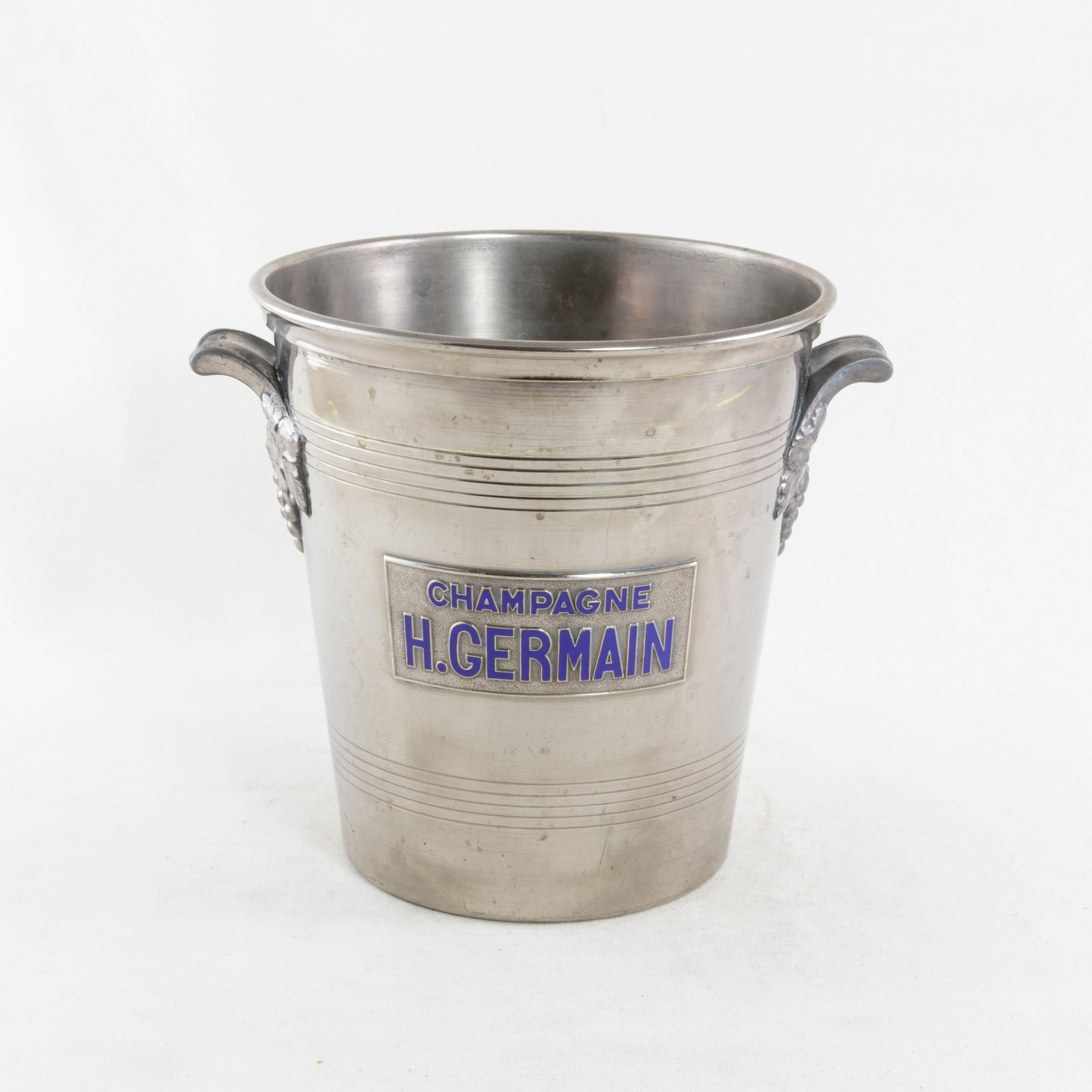 This mid-20th century French silver plate champagne bucket features a blue enameled label marked H. Germain, the name of a champagne production house founded in the late nineteenth century. Handles on each side display decorative clusters of grapes