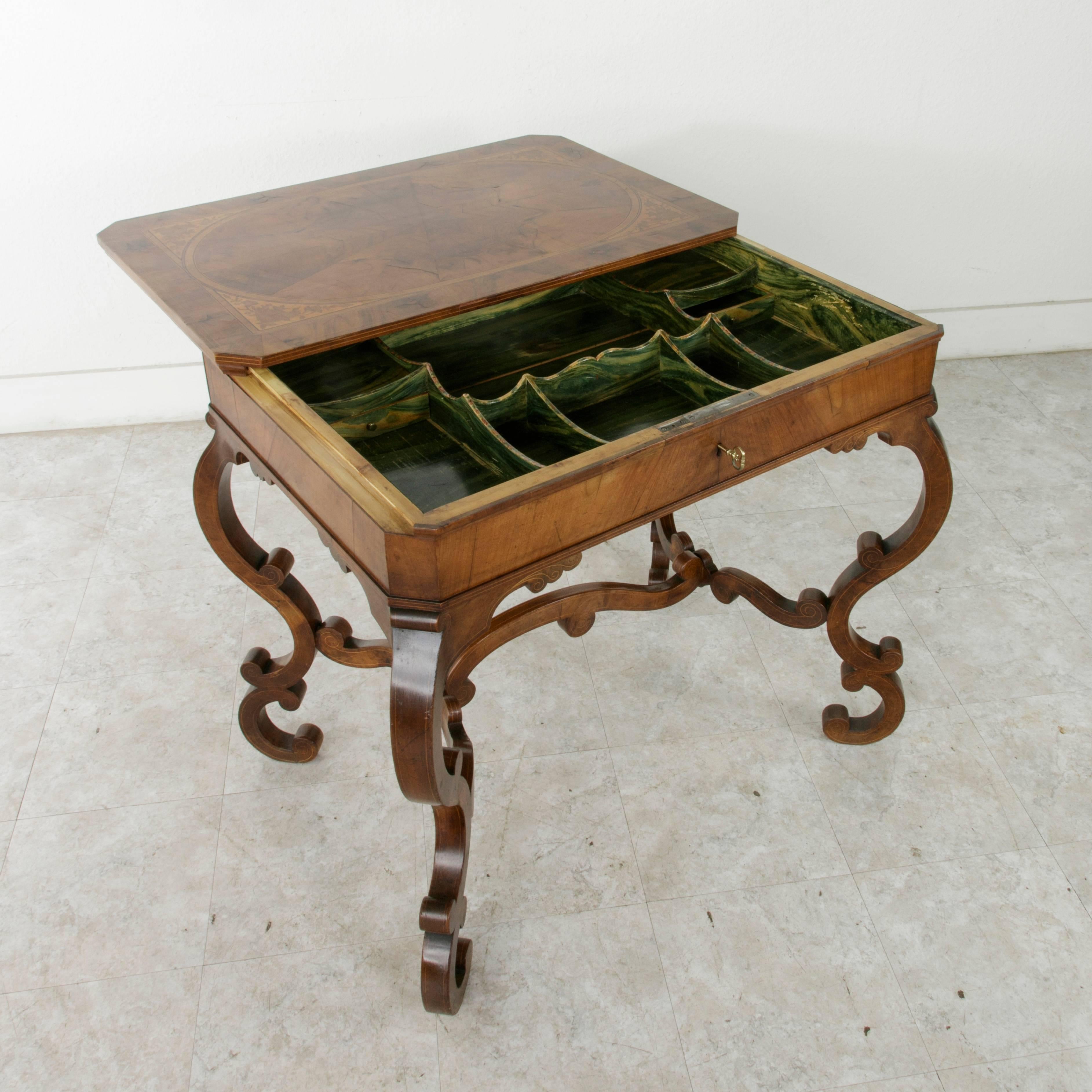 This 18th century walnut and lemon wood marquetry table from Italy was originally used by a money changer. The characteristic feature of a money changer's table is its top which slides forward, obliging the client to step away while the money