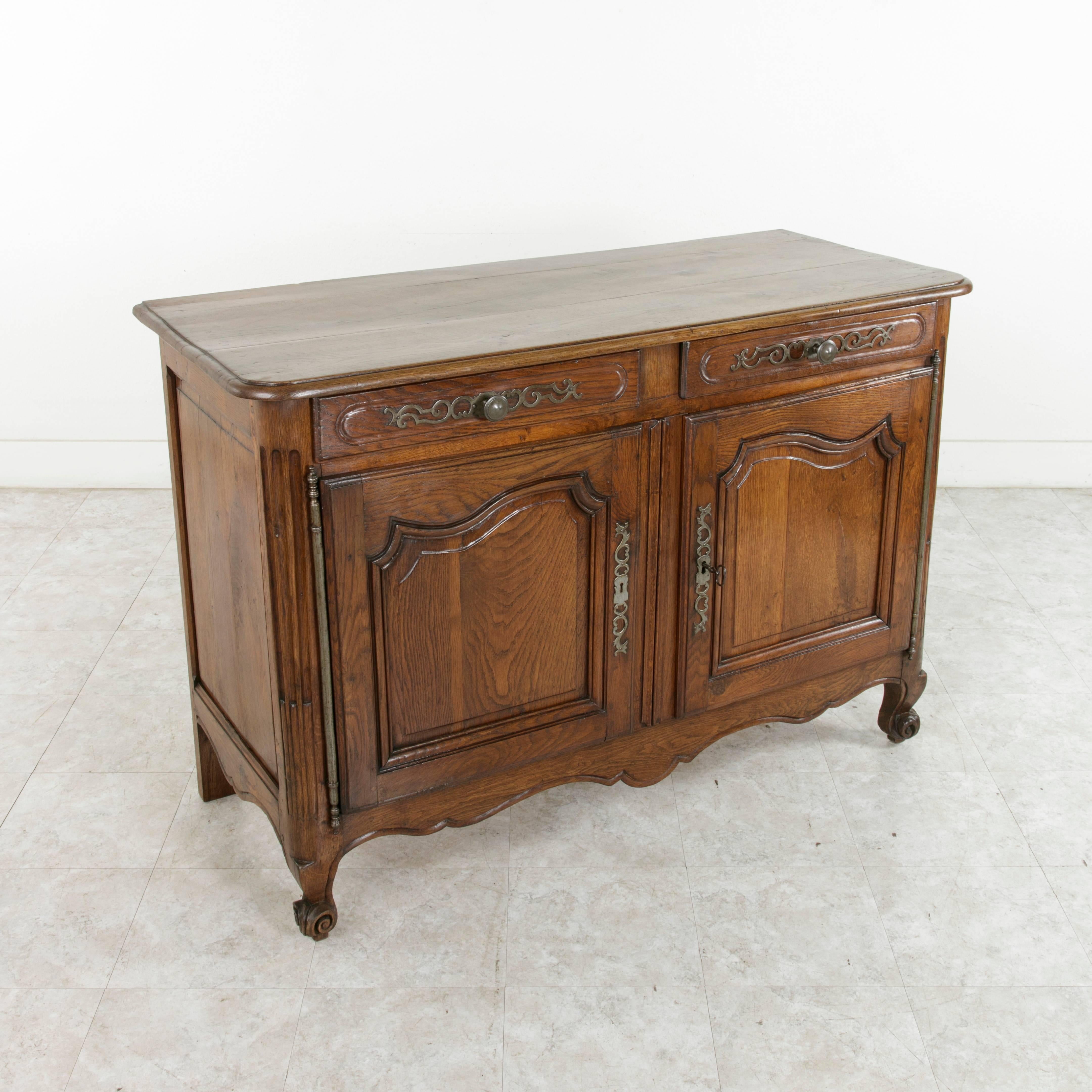 This late 19th century Louis XV style hand-carved oak buffet from Normandy, France, features hand pegged panelled sides and doors and cable fluted rounded corners. A bevelled top and cabriole legs with scrolled feet complete the look. Its original