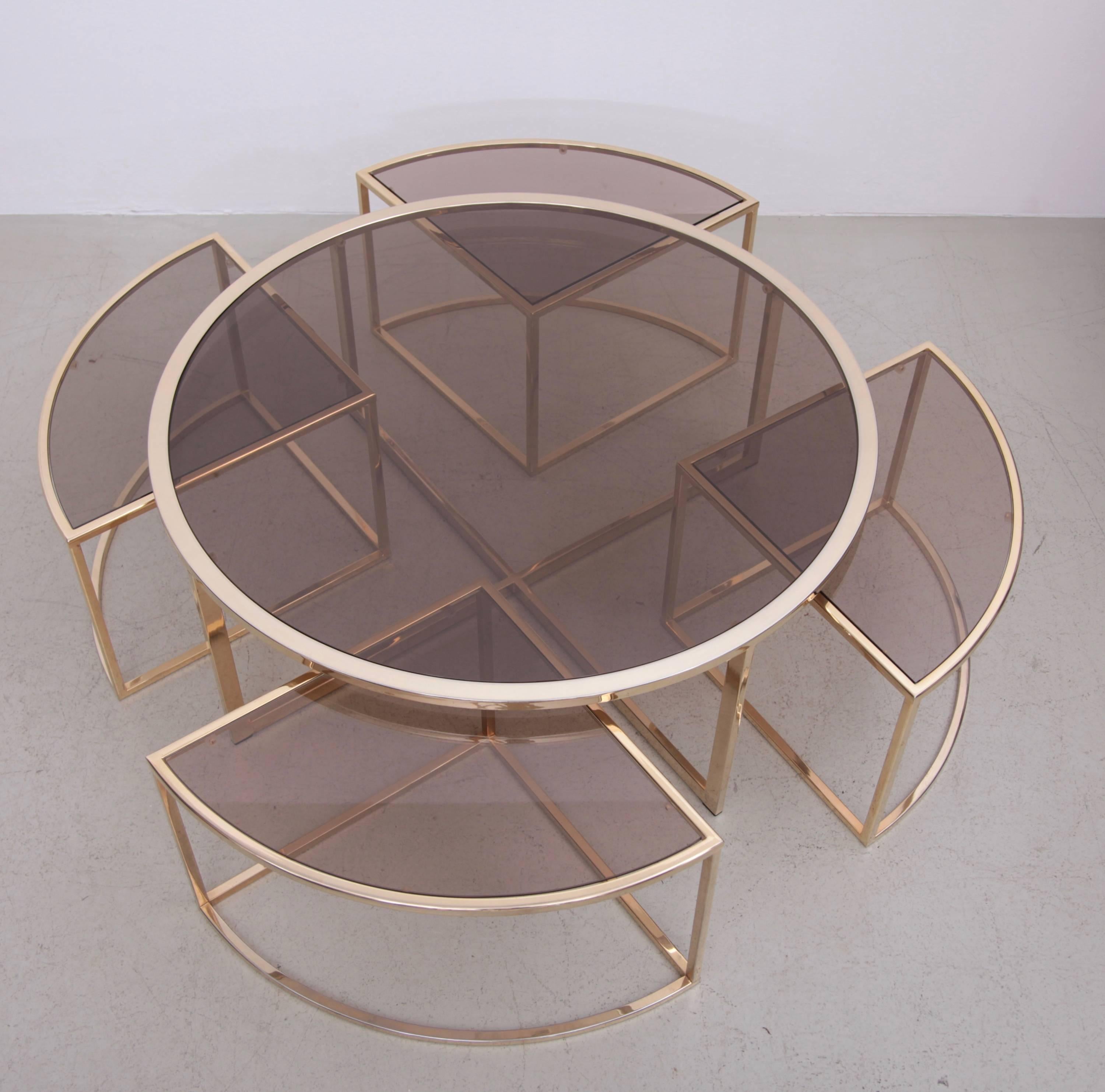 Rare round brass coffee table with four nesting tables by Maison Charles. The glass plates are loosely inserted to create the table surfaces. Excellent condition with tiny glass chips.