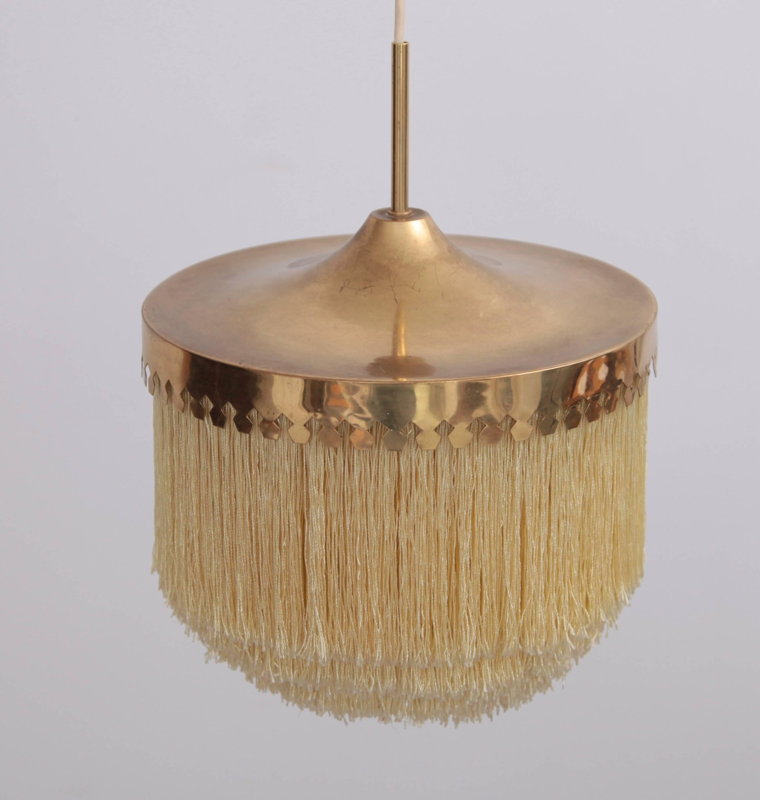 Pendant light with cut brass canopy and ivory-colored silk fringes. Good condition with signs of wear in line with age to both the brass and the silk.
One x E27 / Model A Bulb.