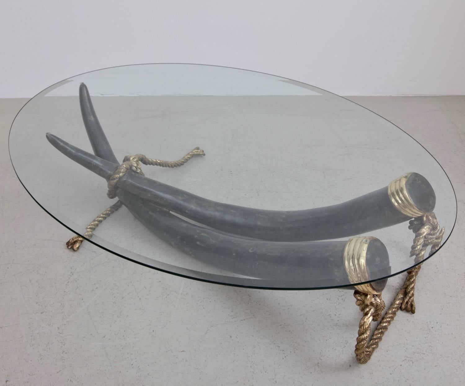 Huge elephant tusk coffee table with oval glass top. Tusks are made of bronze and brass fittings. High quality production in excellent condition. Two pieces available.

