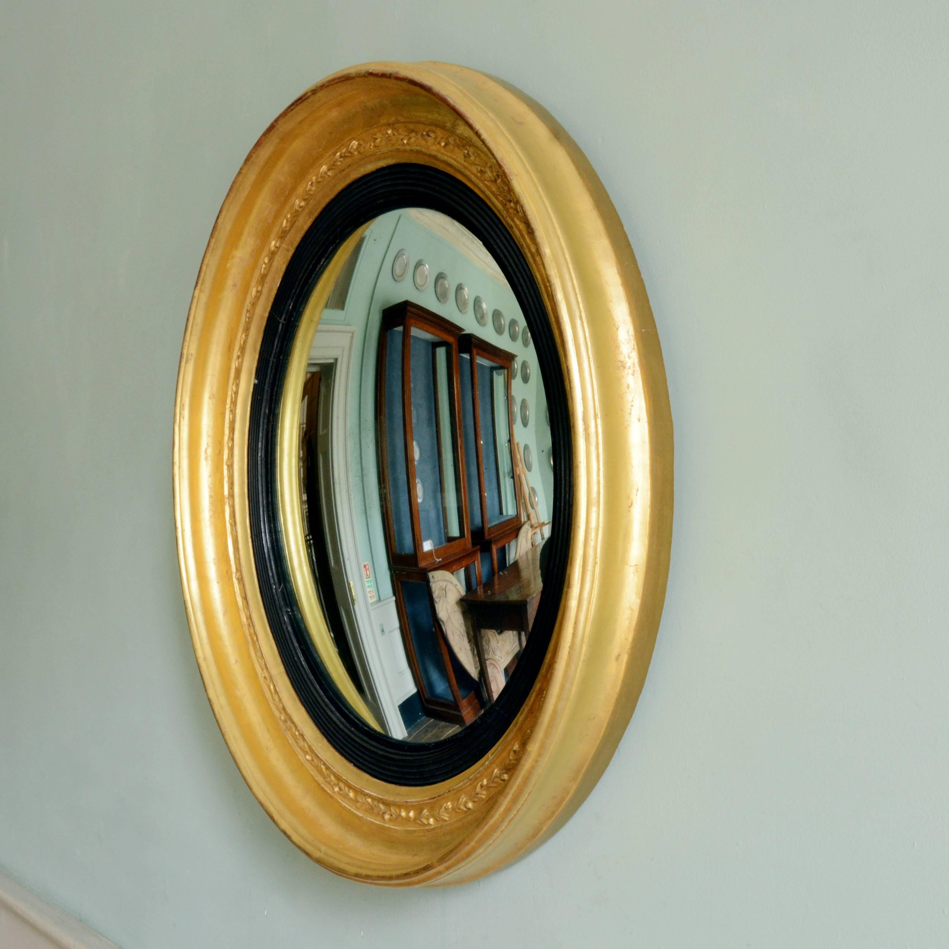 A Regency giltwood convex mirror, early 19th century, with reeded and ebonized slip.

Dimensions: 75cm (29½