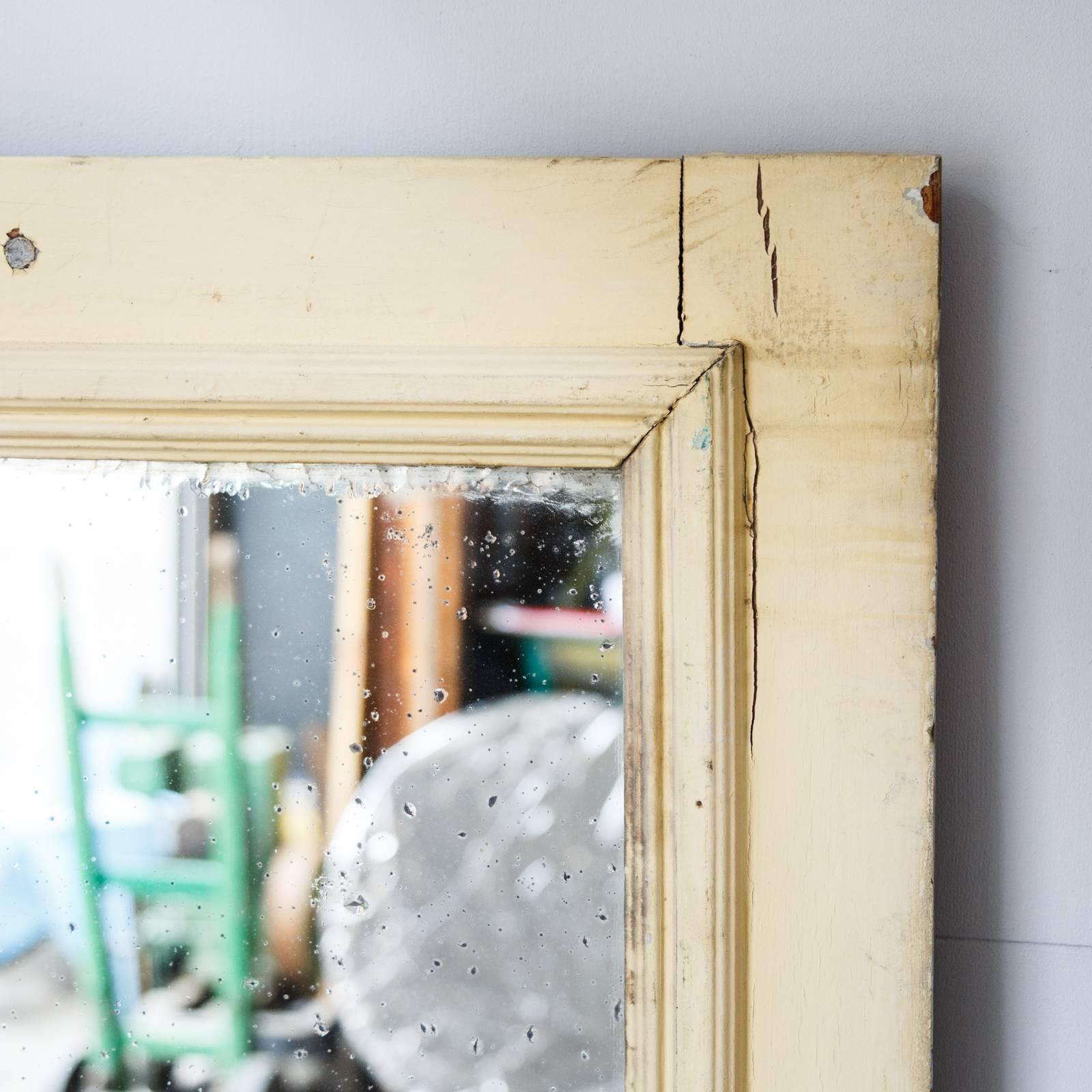 The tall freestanding French mirror features distressed yellow painted pine frame and foxing to the glass.