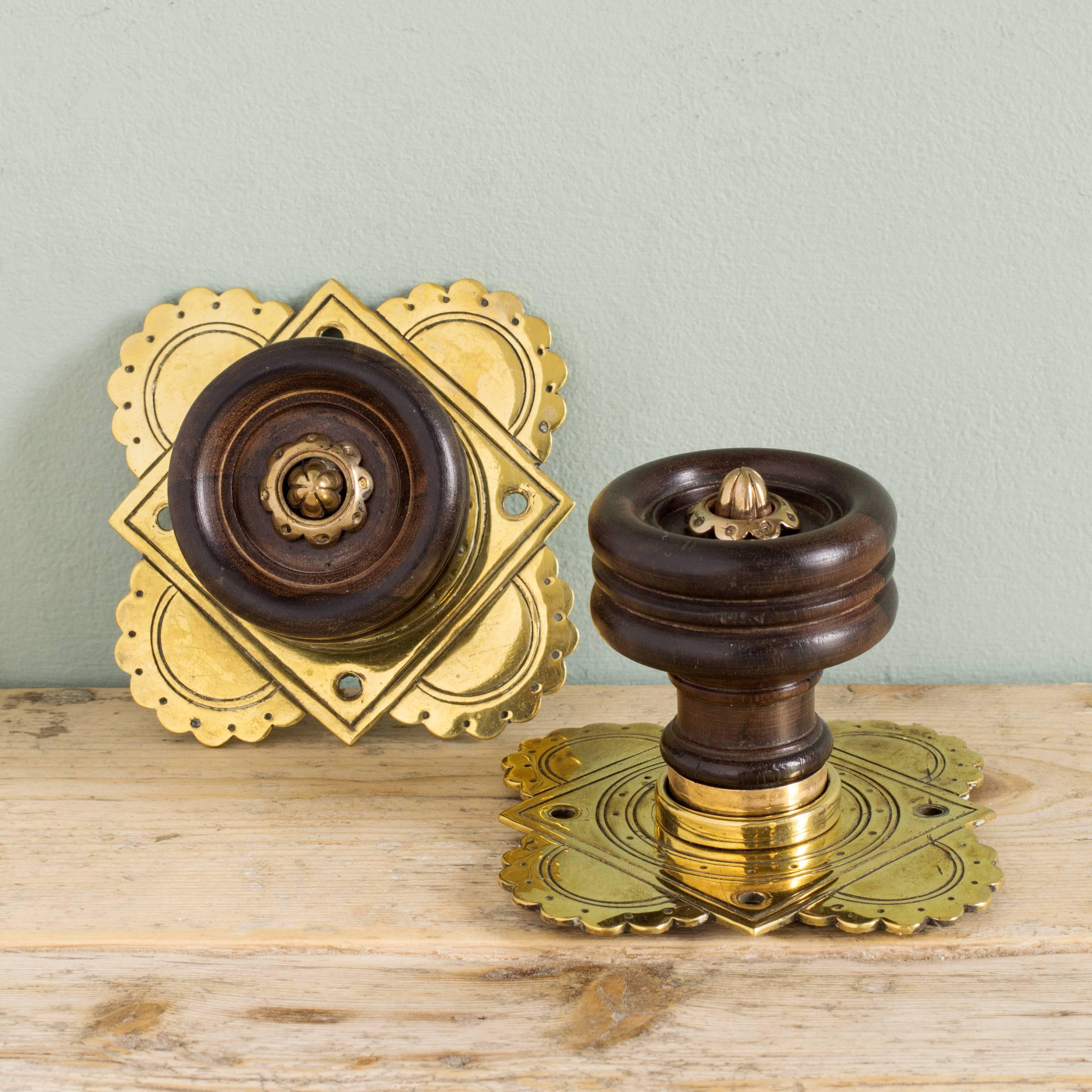 Gothic Revival door handles from the Midland Grand Hotel, London, designed by Sir George Gilbert Scott, circa 1873, the turned ebony handle centred by brass boss with decorative fret cut and engraved backplates. Seven pairs and one single
