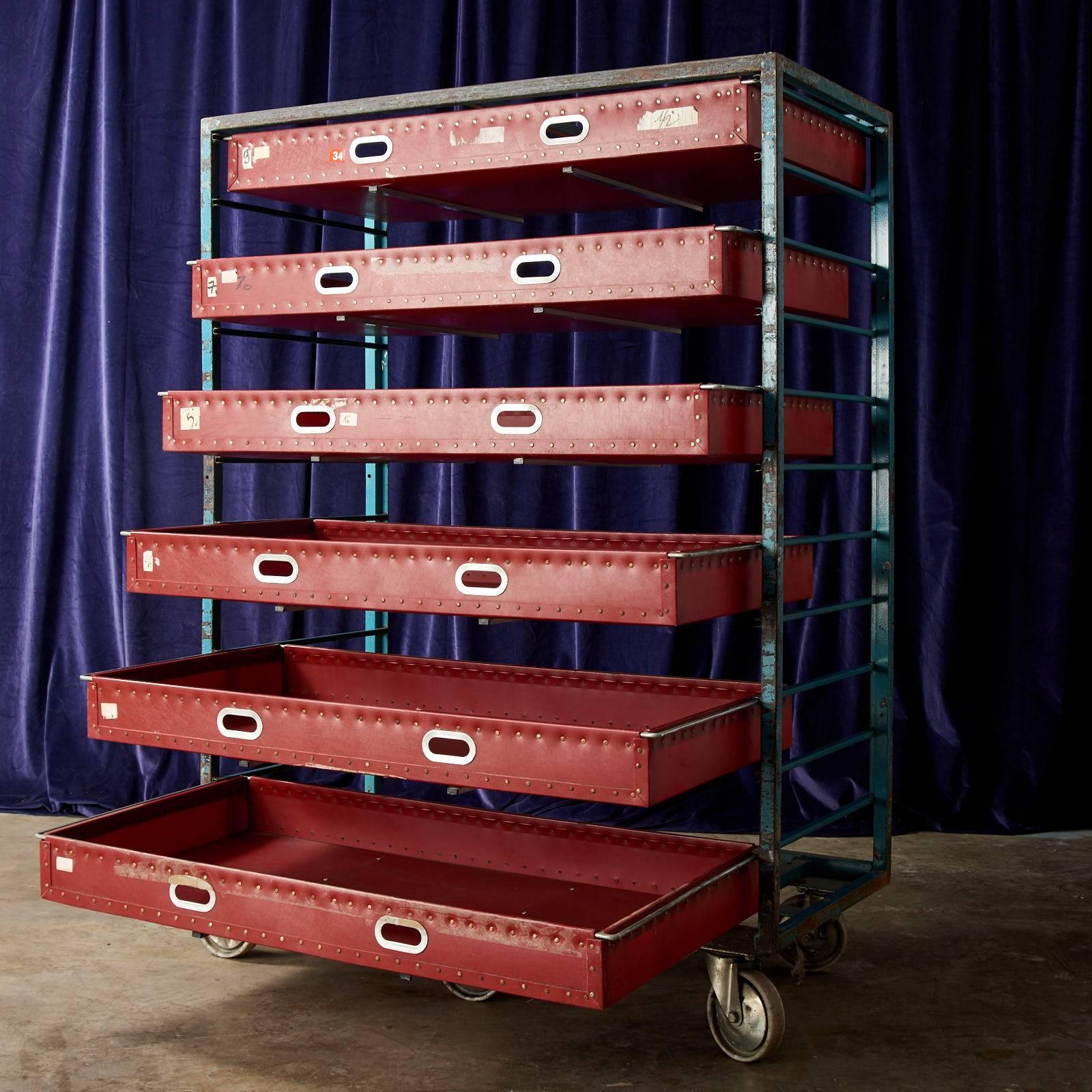 This Industrial steel and vinyl textile trolley features and number of drawers and sits atop a set of six castors.