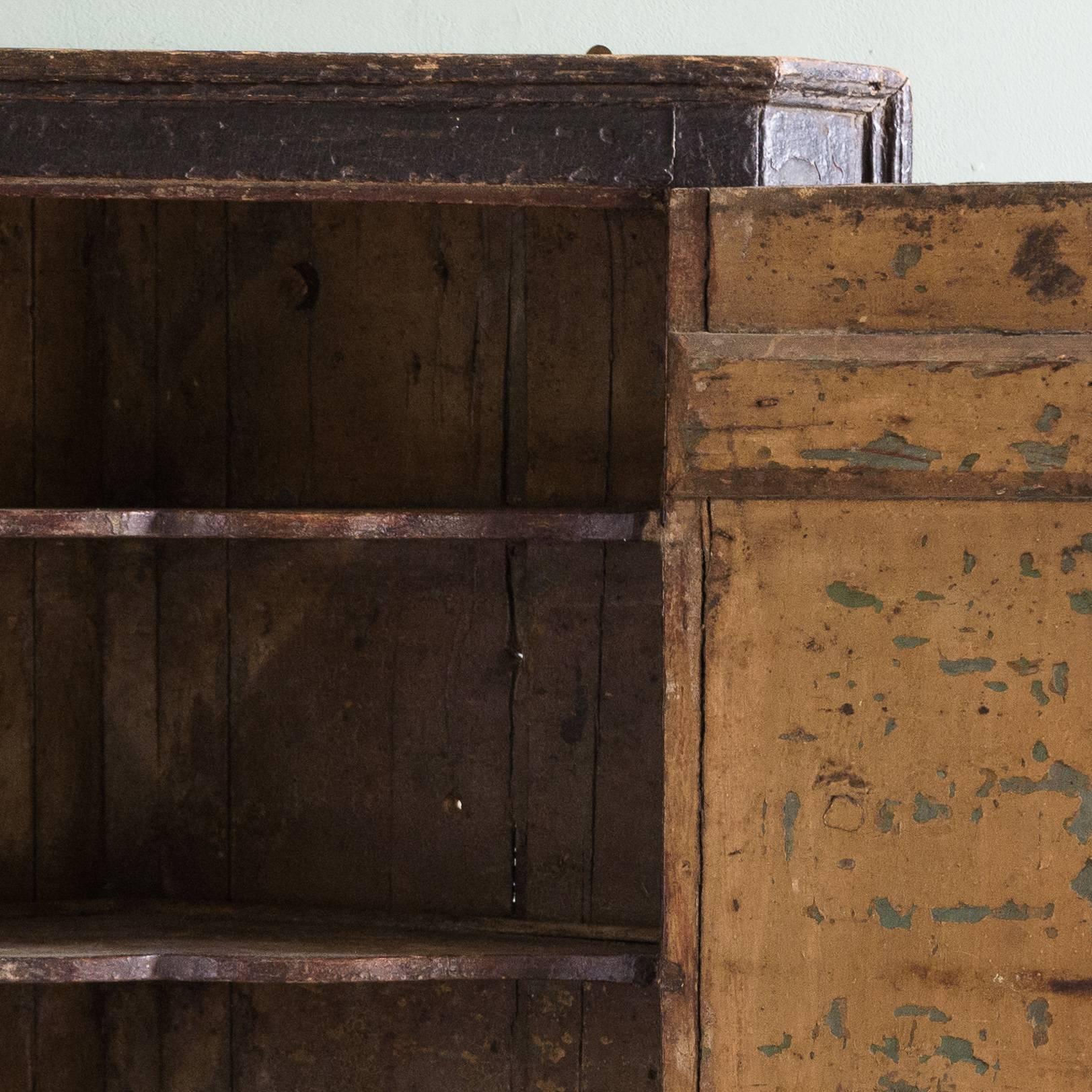 Mid-18th century hanging corner cabinet with extant old painted surfaces to interior and exterior, fitted with cupid's bow shelves.

Dimensions: 91.5cm (36") high, 73cm (28¾") wide, 43cm (17") deep.