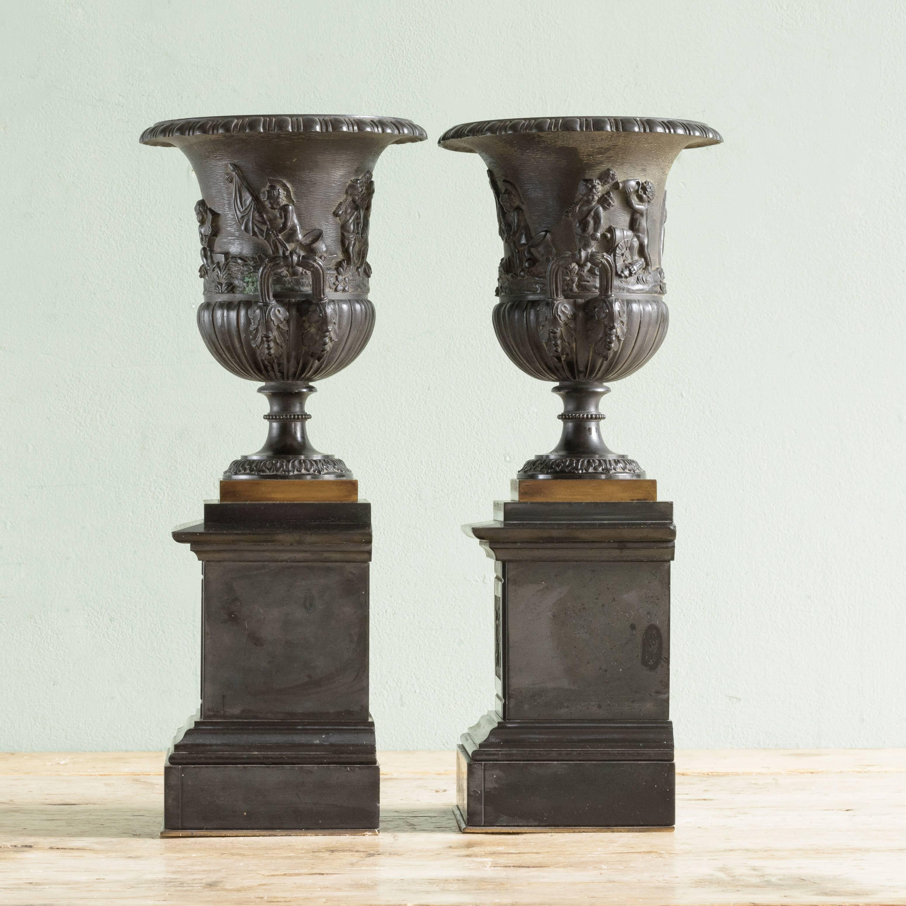 Pair of French, 19th century bronze and slate garniture de cheminée, the urns of campana form raised on decorated slate pedestals.